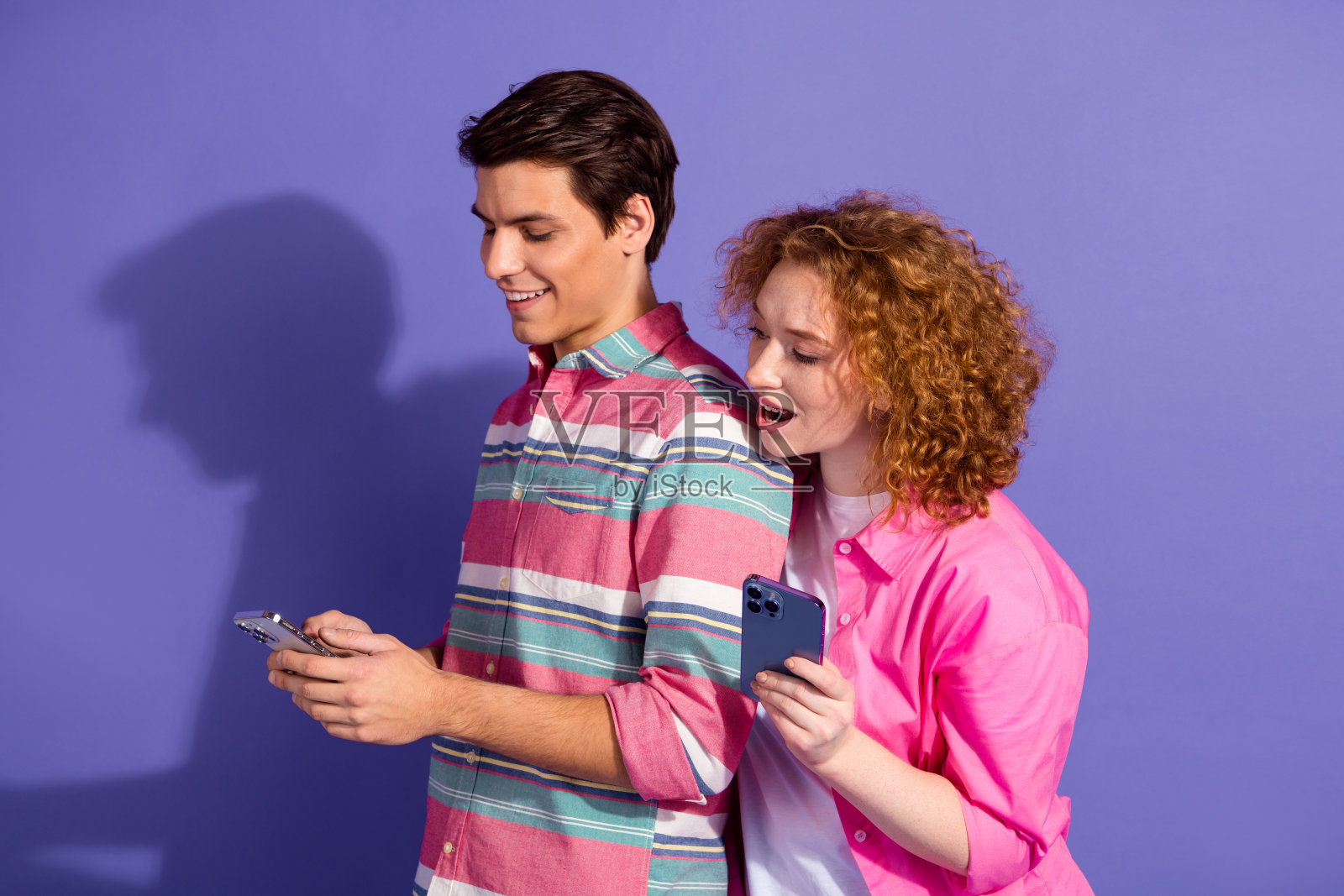 快乐的年轻朋友们在充满活力的紫色背景下一起使用智能手机,享受休闲时光照片摄影图片