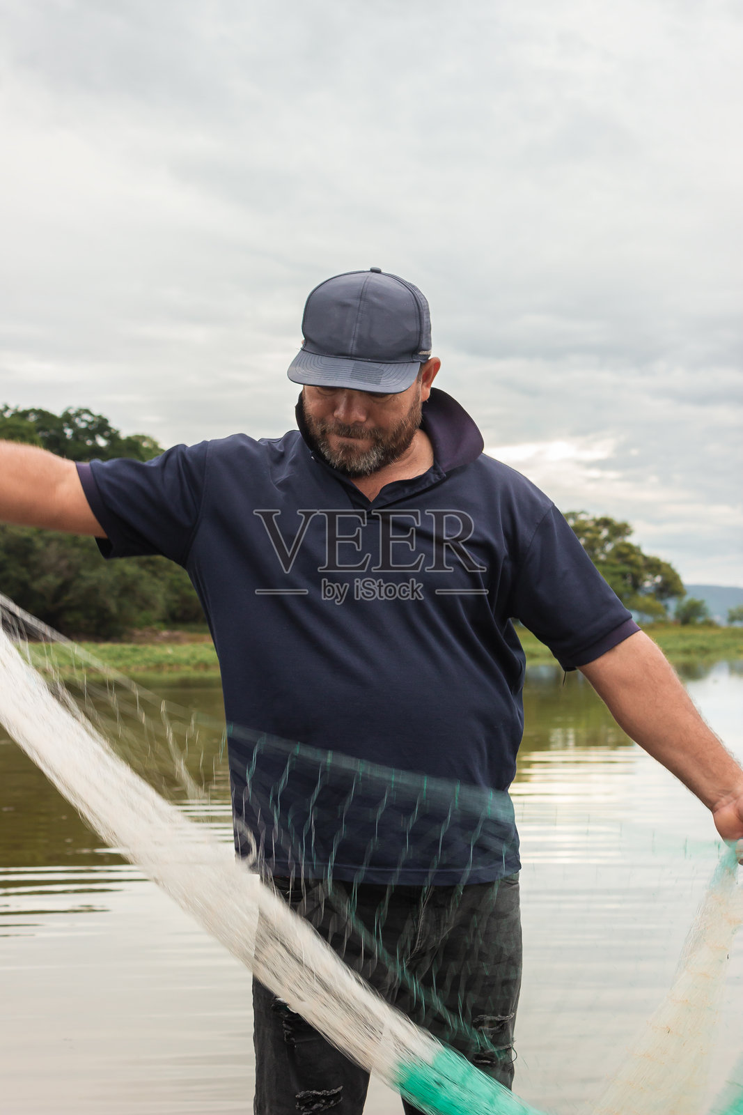 一位渔民在水坝上拿着撒网照片摄影图片