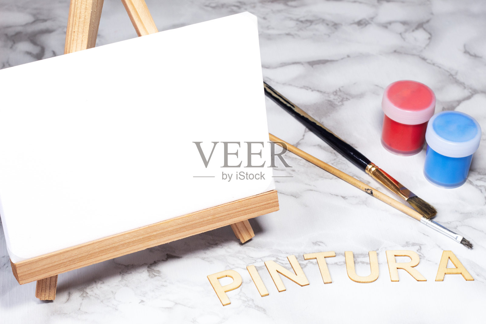 空白画布与画笔和颜料罐,西班牙语“绘画”字样的木字母,艺术课程的创意摄影照片摄影图片