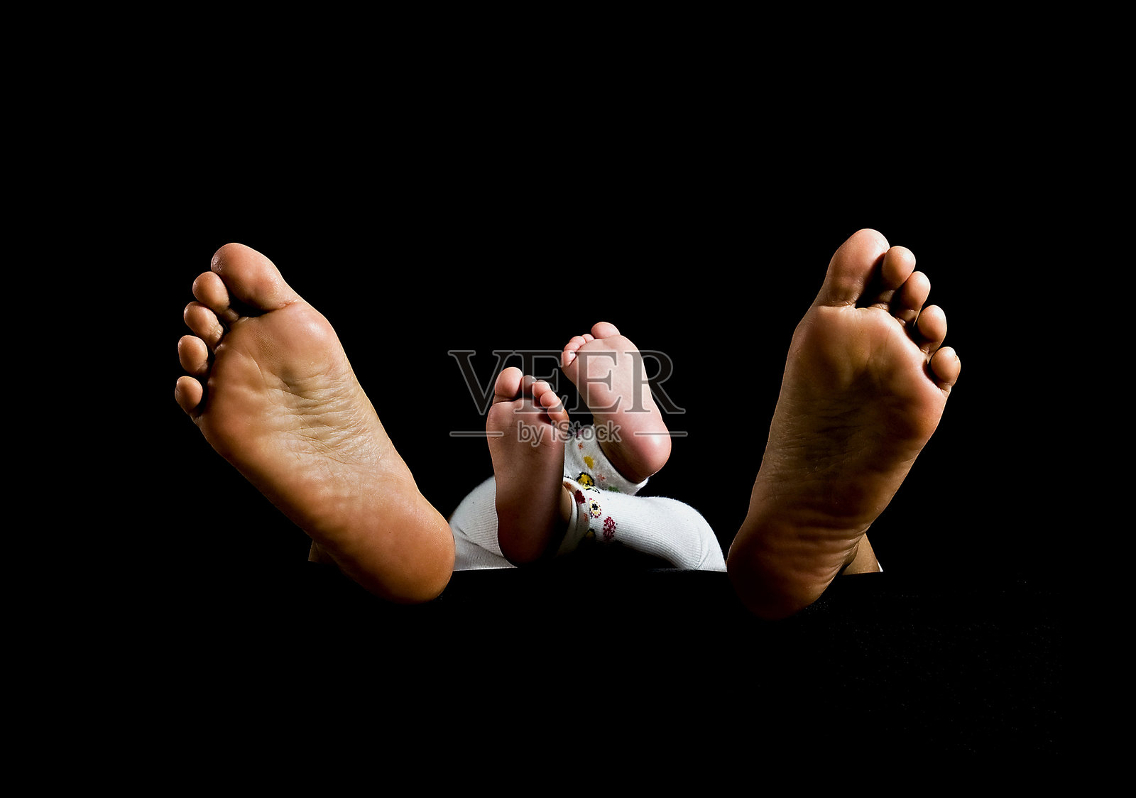 一对新生儿的脚与母亲的脚在黑色背景上独立展示照片摄影图片