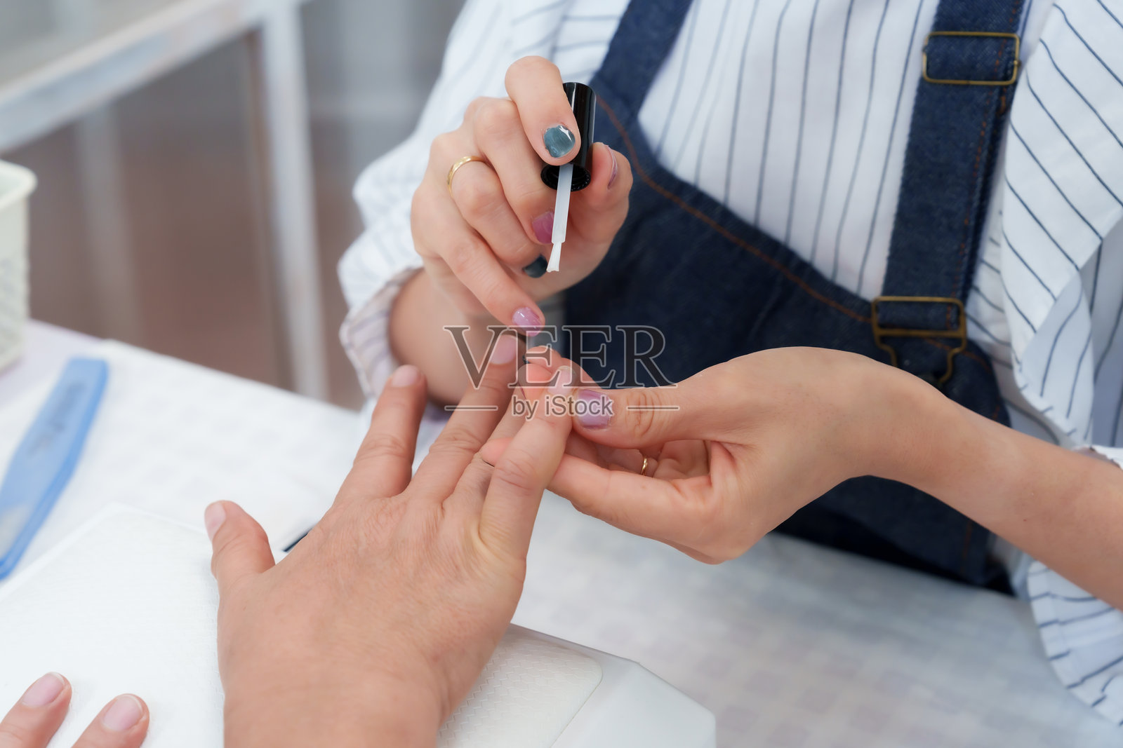 美甲水疗工作人员在温馨的美甲过程中为一位年长的亚洲女性修指甲,宣传美容、个人护理、卫生、健康、放松的生活方式,适合在小型专业友好的沙龙中进行的护理。照片摄影图片