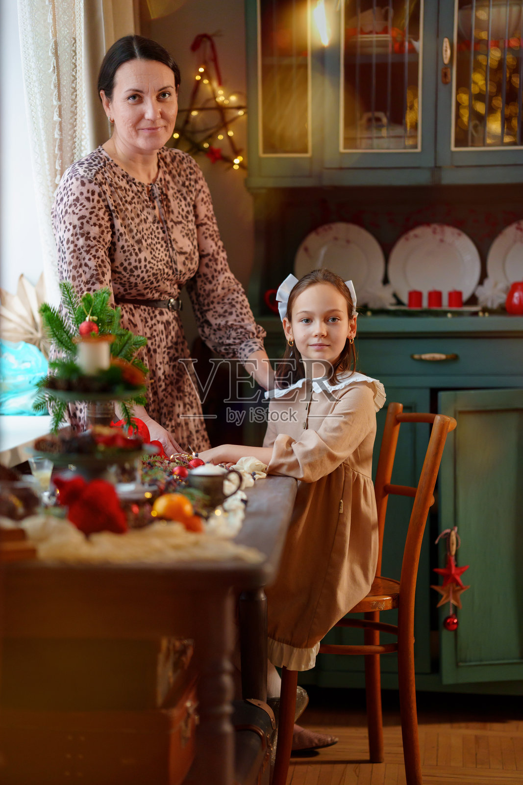 母女在节日的新年餐桌旁。照片摄影图片