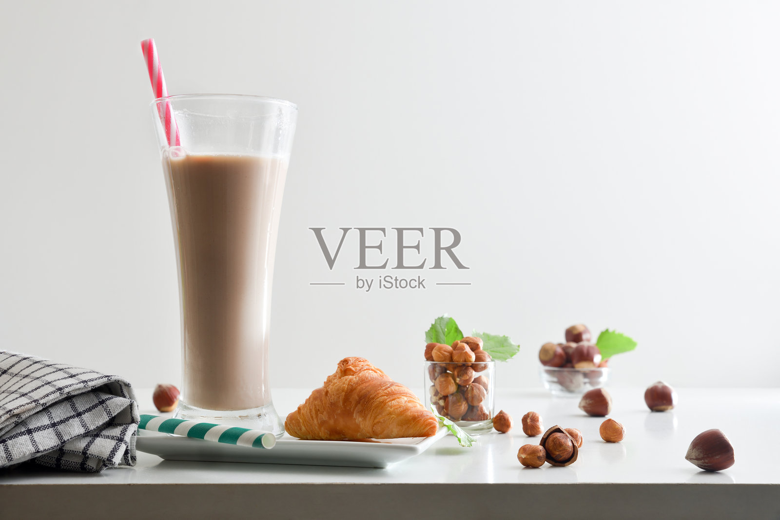 桌子上的榛子饮料和可颂面包,背景为白色纯色。照片摄影图片