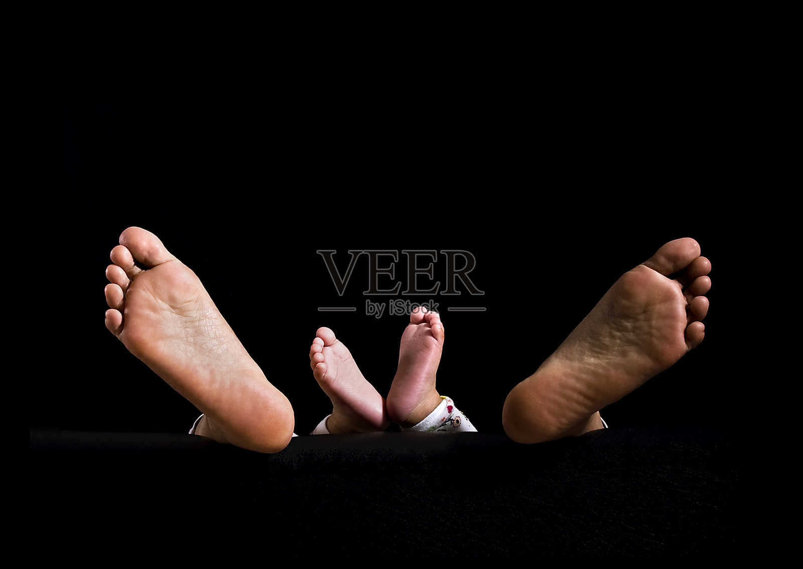 一对新生儿的脚与他母亲的脚在黑色背景上独立展示照片摄影图片