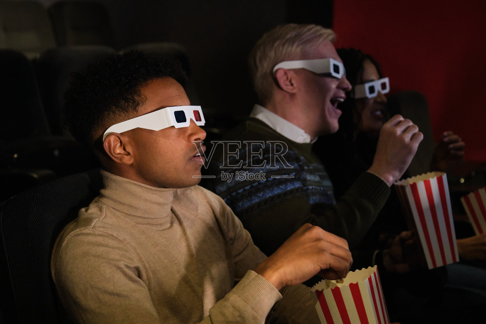 朋友们在电影院观看3D电影并吃着爆米花照片摄影图片
