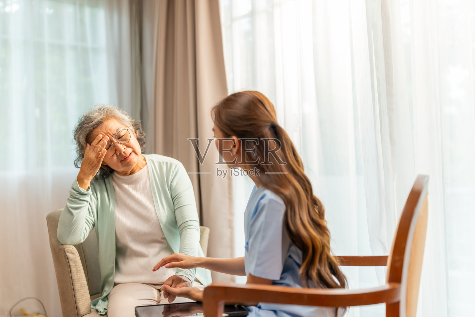 亚洲老年女性在家中与精神科医生交谈。照片摄影图片