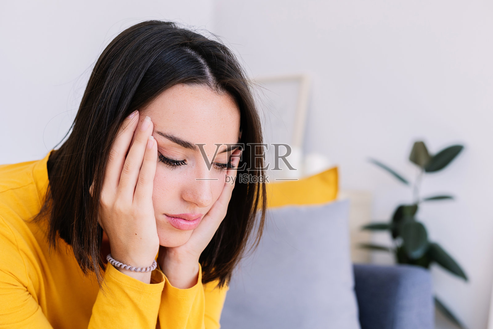 忧虑的年轻漂亮女性坐在家中的沙发上沉思照片摄影图片