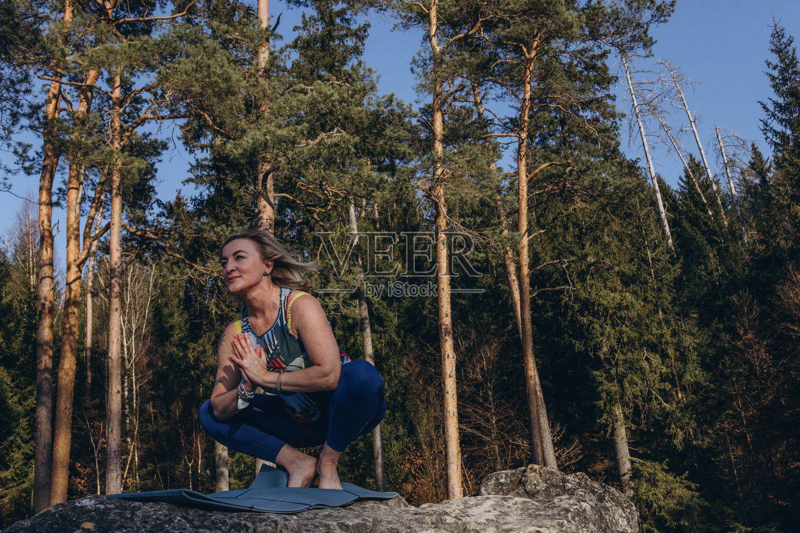 一位女性在日落时分坐在岩石上冥想和练习瑜伽,拥抱健康、正念和环保生活。照片摄影图片