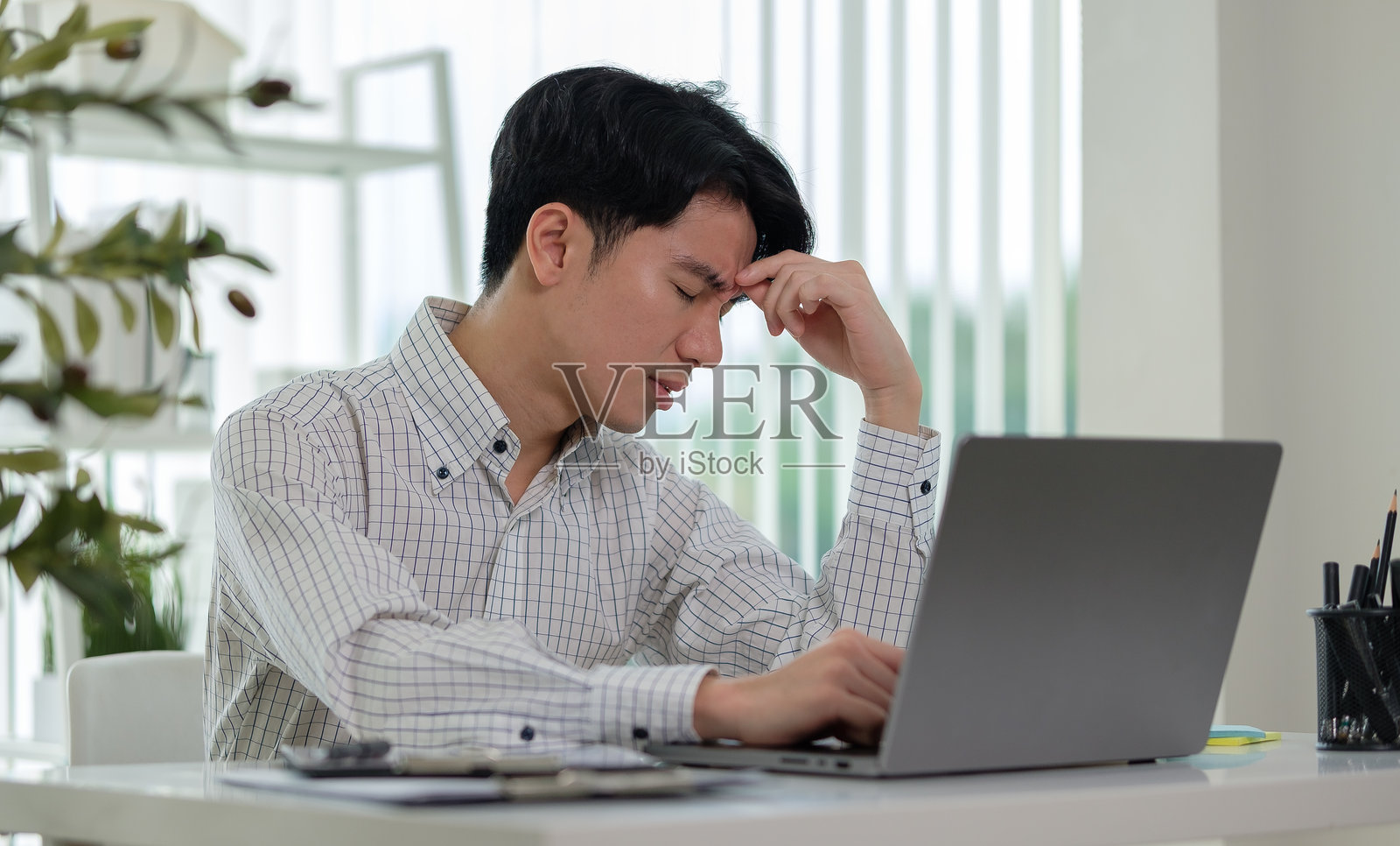 疲惫的商人按摩鼻梁,因电脑工作而感到疲劳。照片摄影图片