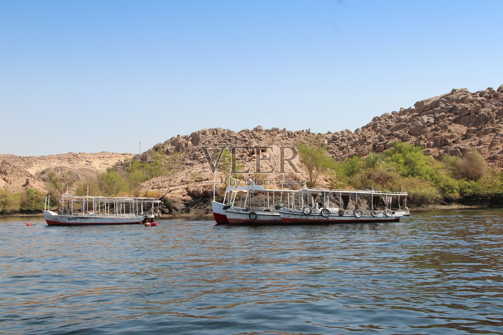 阿吉尔基亚岛的岩石形成景观,附近有船只停靠在菲莱岛。照片摄影图片