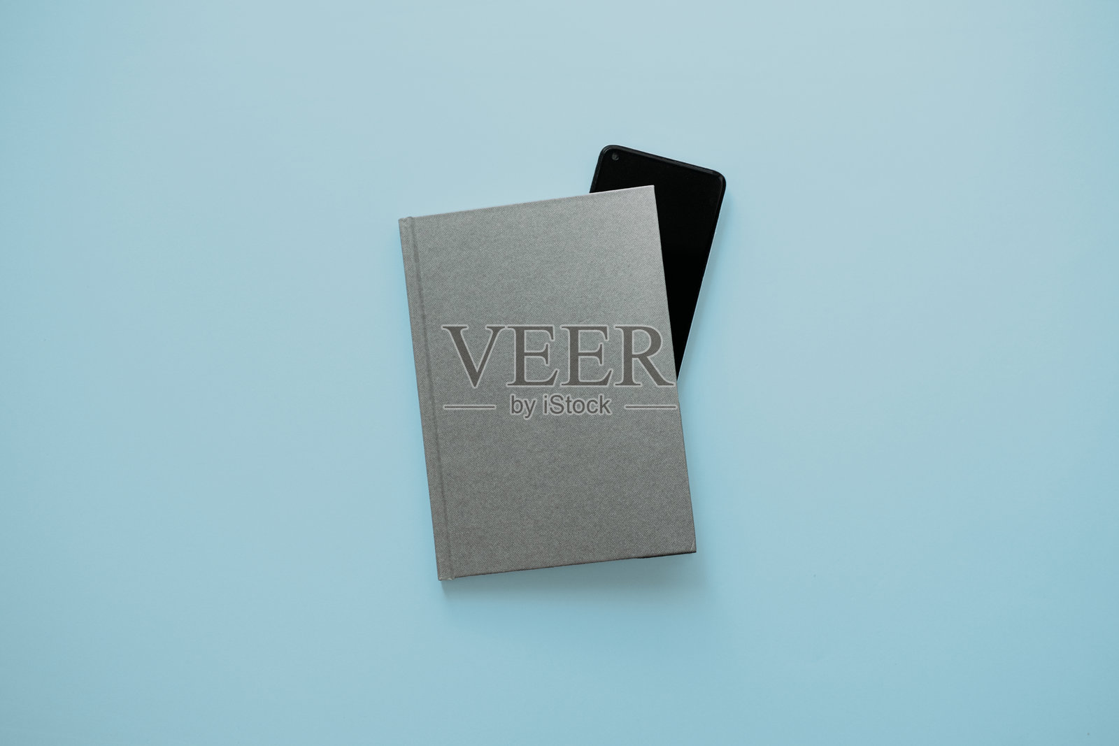 书籍和智能手机在淡蓝色背景上照片摄影图片