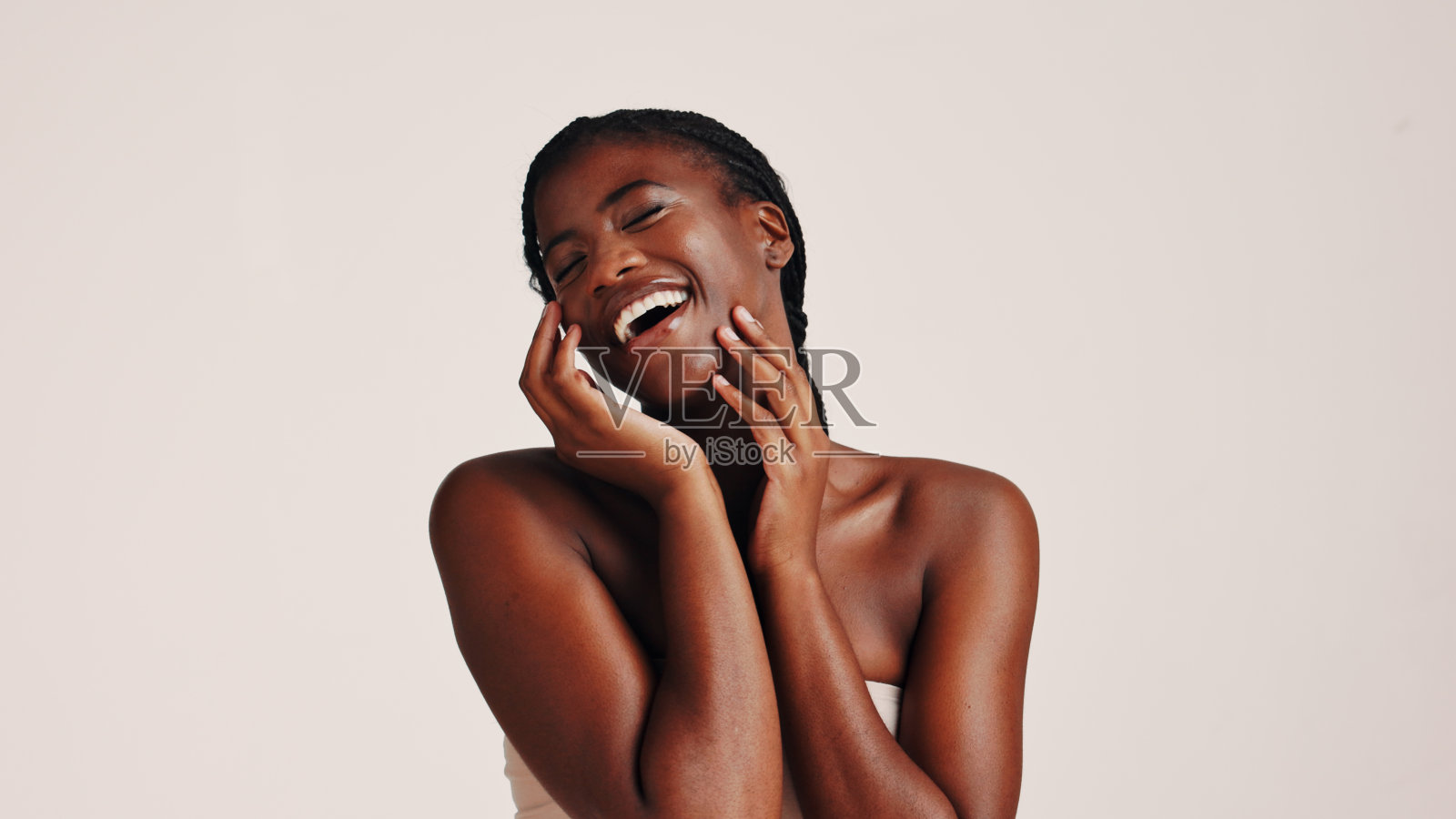 黑女人在美容院里开心地笑,展示护肤和美容,体现光彩、个人护理和胶原蛋白,适合用于水疗治疗和样板空间的白色背景。照片摄影图片