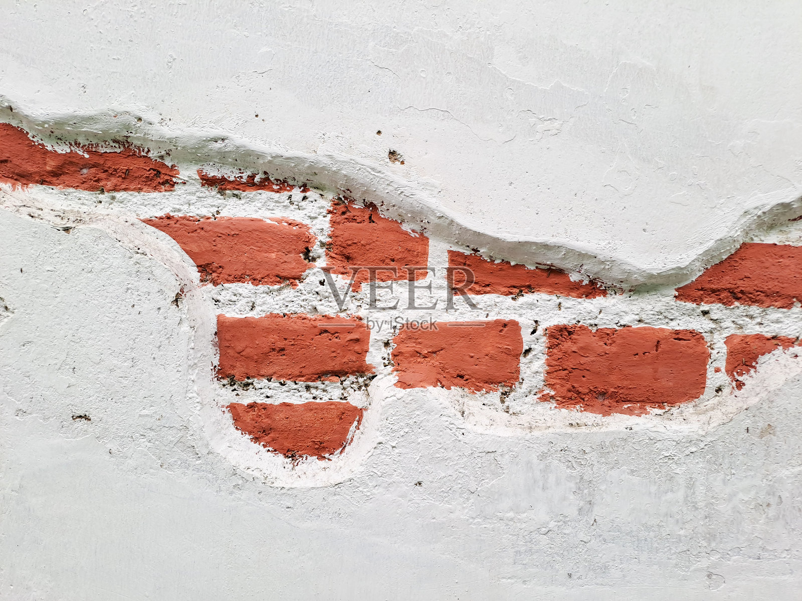 破损的石膏,展现出古老砖墙的纹理。一面风化的砖墙部分被剥落的白色石膏覆盖,露出了下面的红砖。照片摄影图片