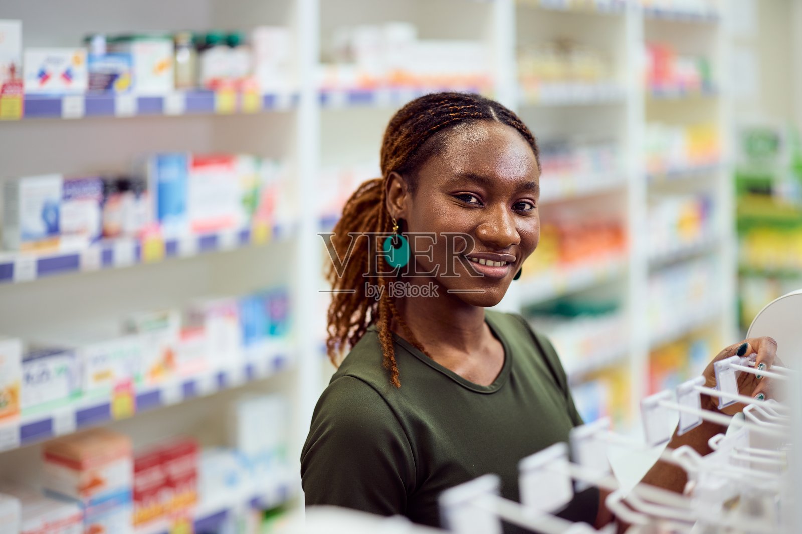 微笑的女性在灯光明亮的药店购物,药品货架整齐有序照片摄影图片