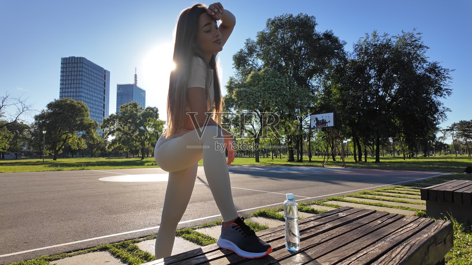 年轻疲惫的女性在城市公园慢跑和锻炼后喝水。照片摄影图片