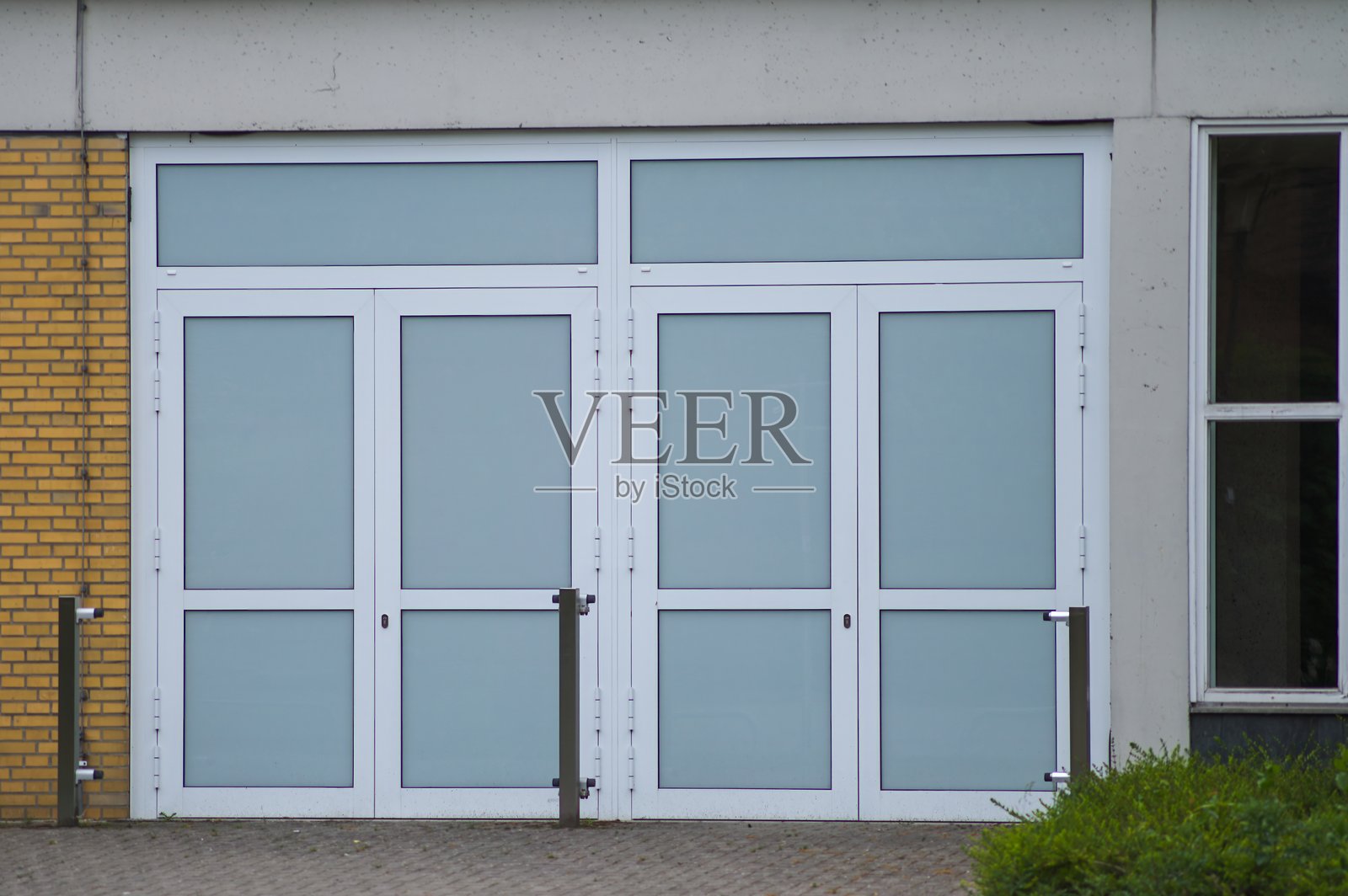 现代建筑入口,配有磨砂玻璃门和混凝土墙。照片摄影图片