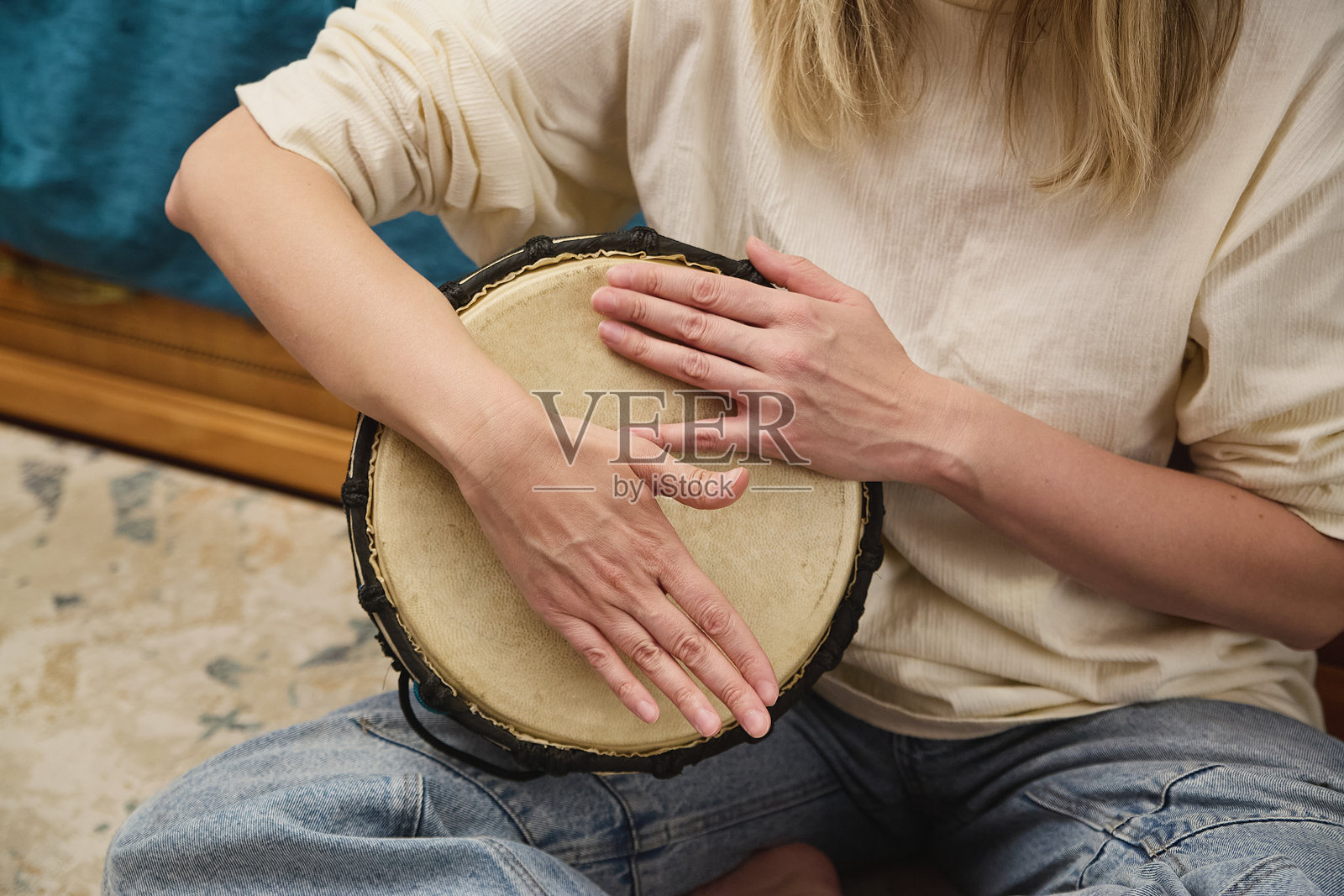 女性在室内打手鼓,展示节奏技巧和音乐表现,享受轻松的即兴演奏时光。照片摄影图片