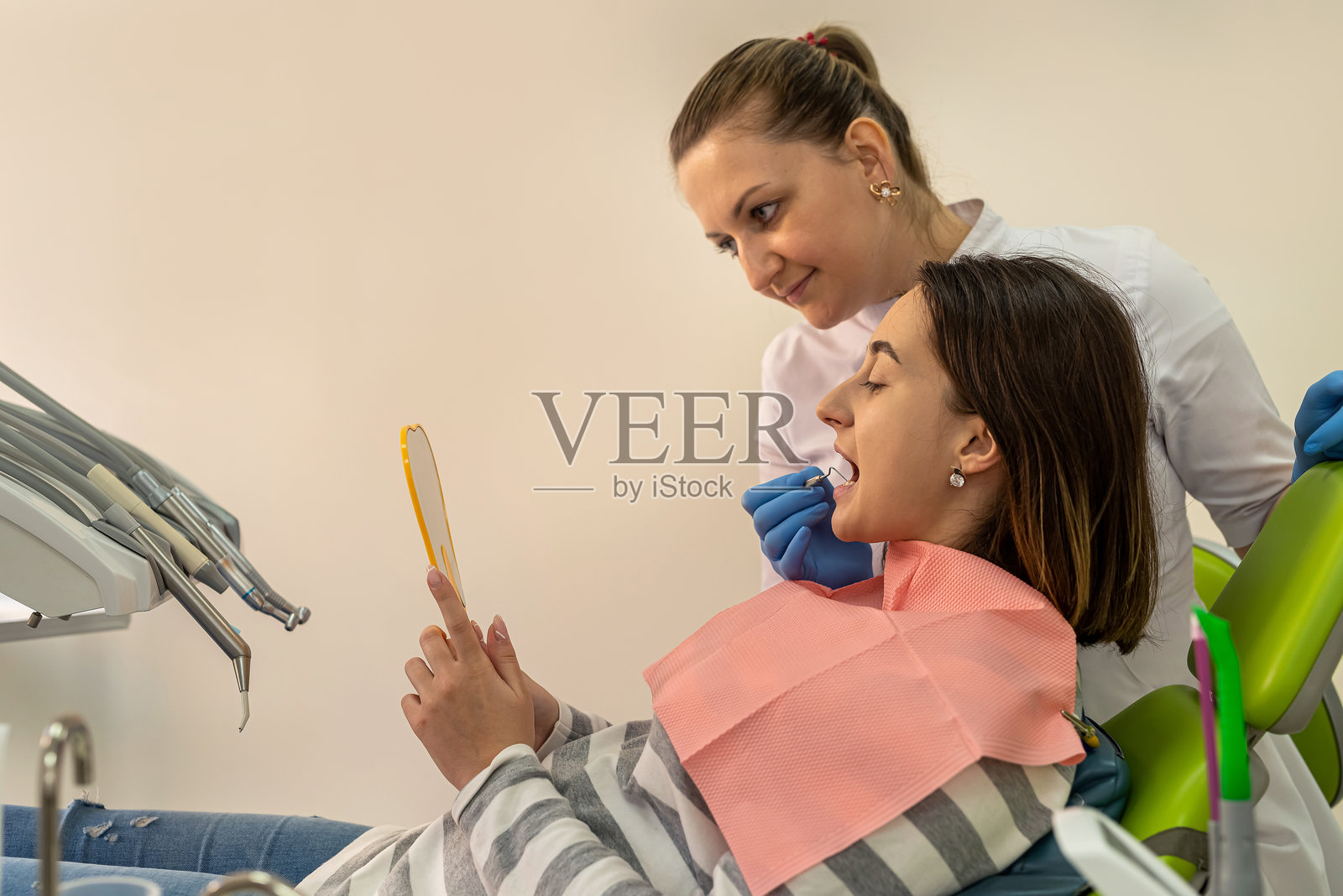 患者和医生正在镜子前讨论治疗龋齿或牙龈疾病。照片摄影图片