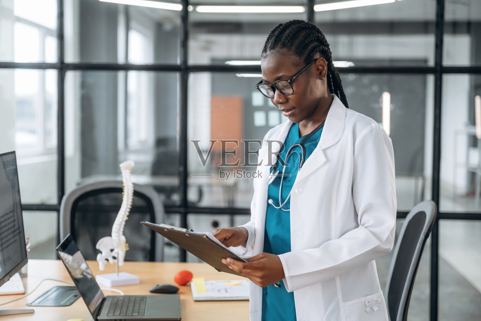 手中拿着记事本的女性。穿着白大褂的女医生在诊所办公室里。照片摄影图片