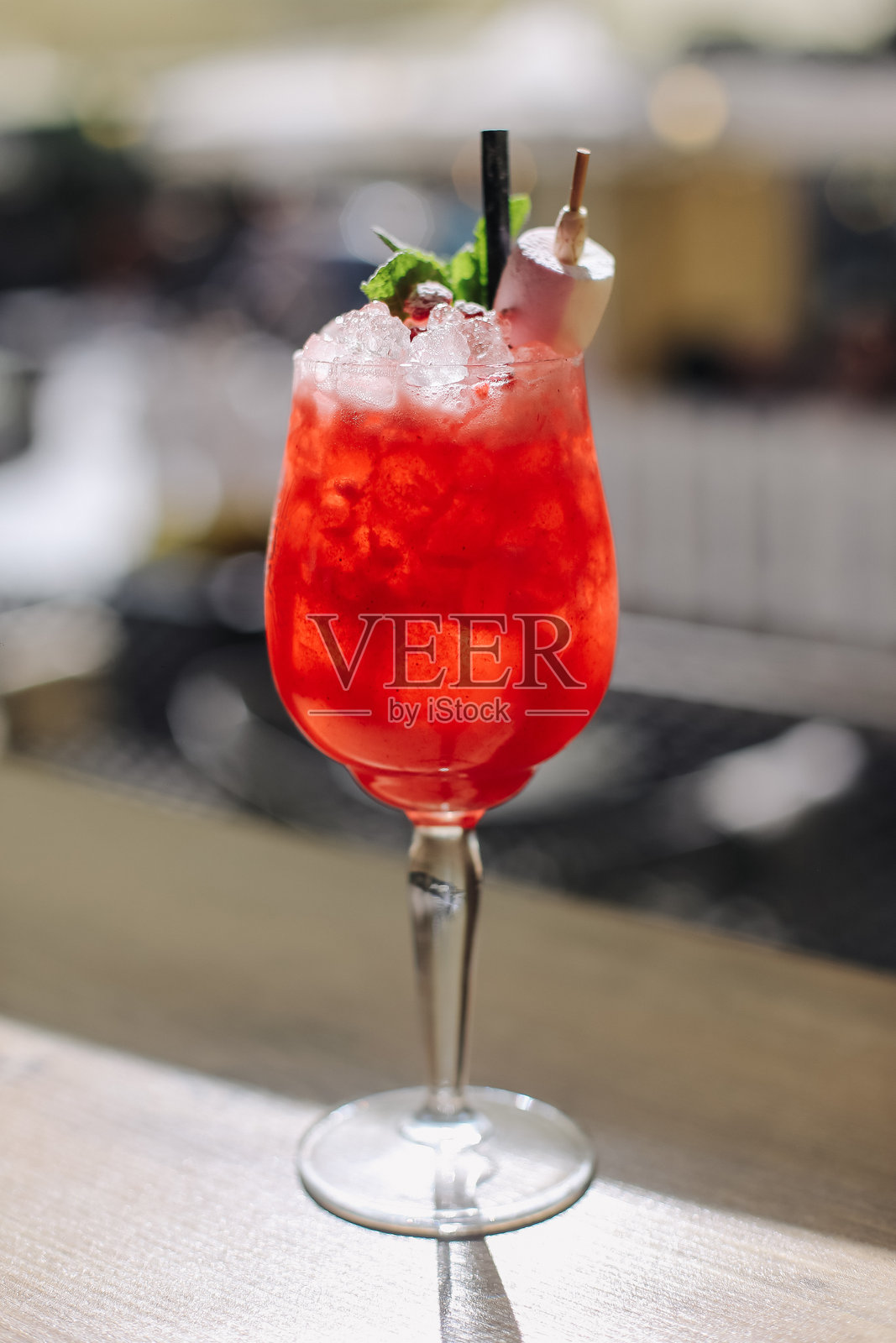 红色鸡尾酒,配冰块,盛在酒杯中。装饰有薄荷。配有吸管和串签。清爽的夏季饮品。照片摄影图片
