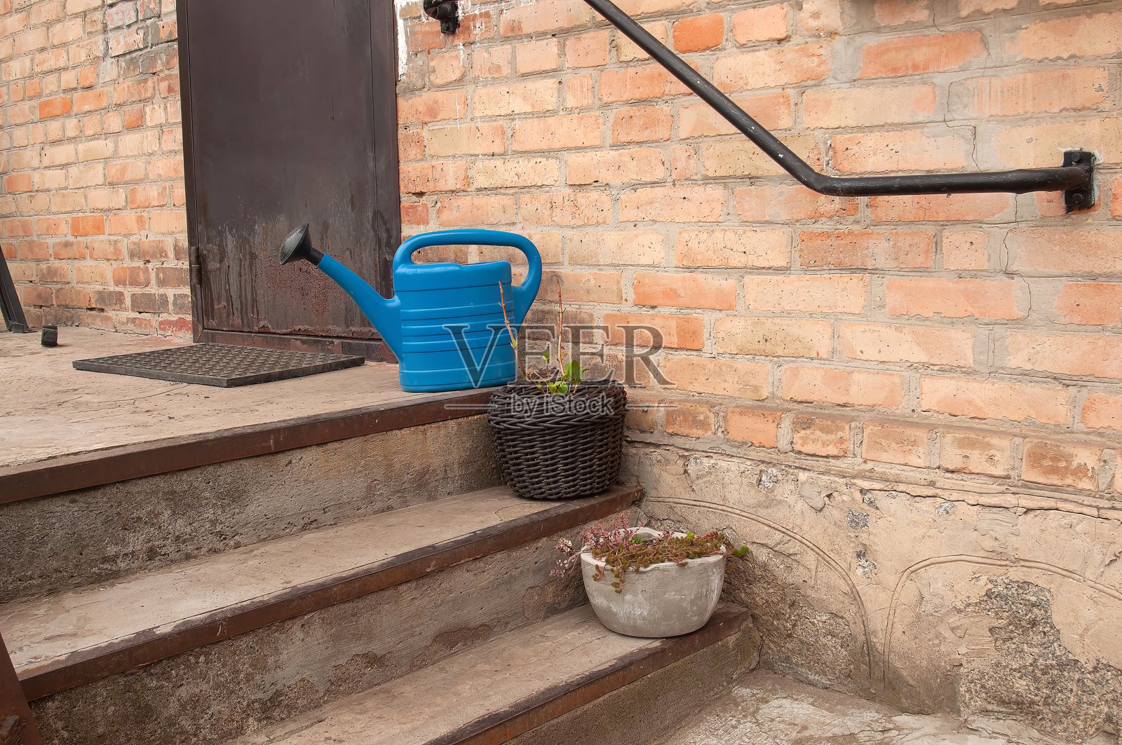 迷人的户外场景,砖砌台阶、蓝色浇水壶和盆栽植物。照片摄影图片