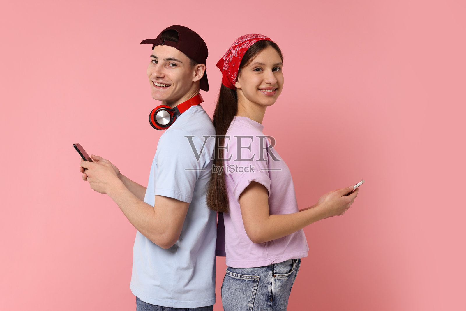 粉色背景下拿着智能手机的学生肖像照片摄影图片