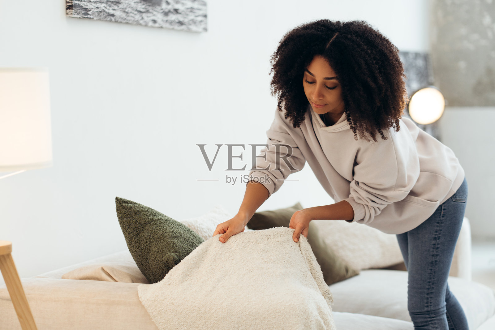 年轻女性在客厅里整理沙发上的舒适毯子照片摄影图片