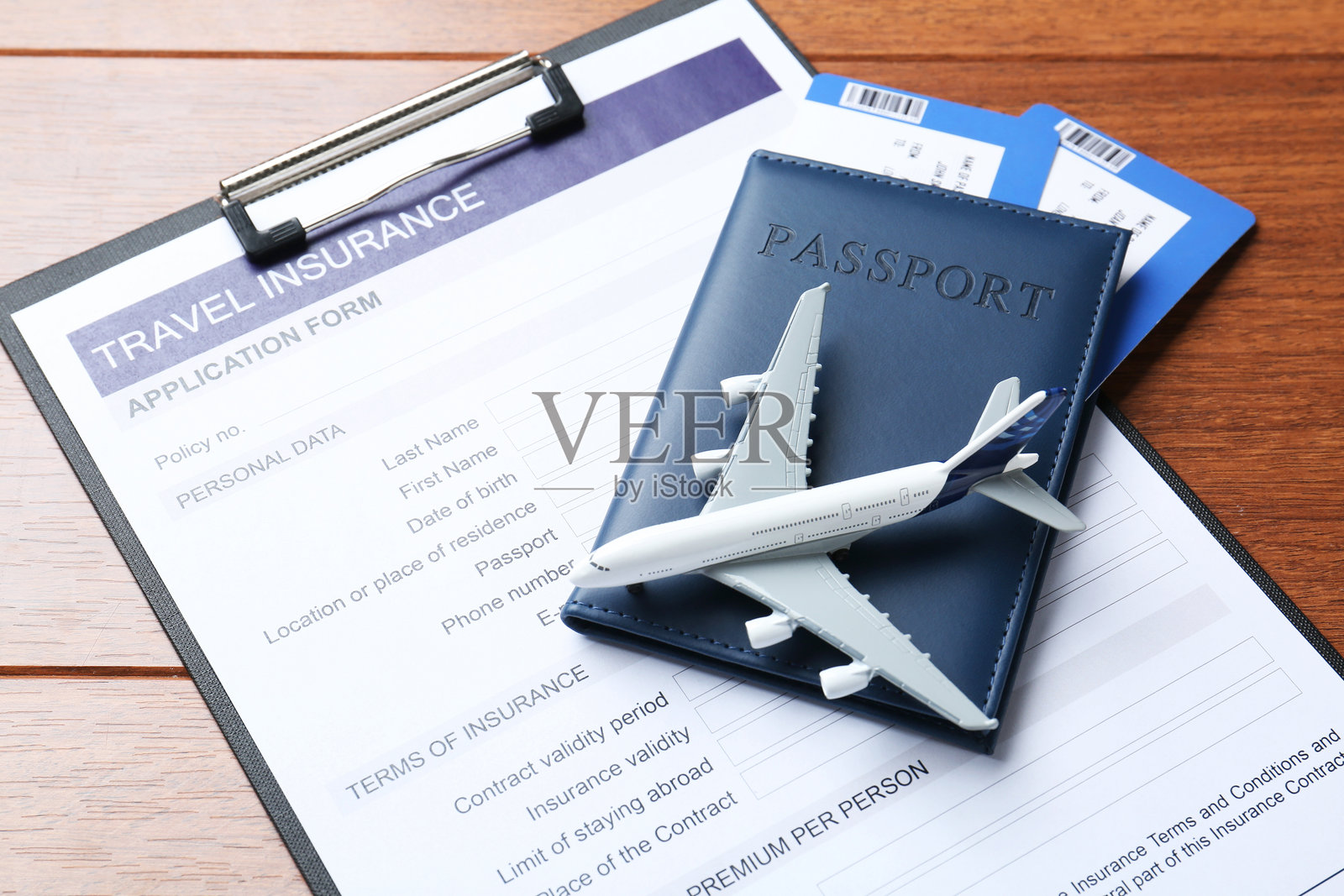 医疗旅游。旅行保险申请表、护照、机票和木质背景上的飞机模型特写。照片摄影图片
