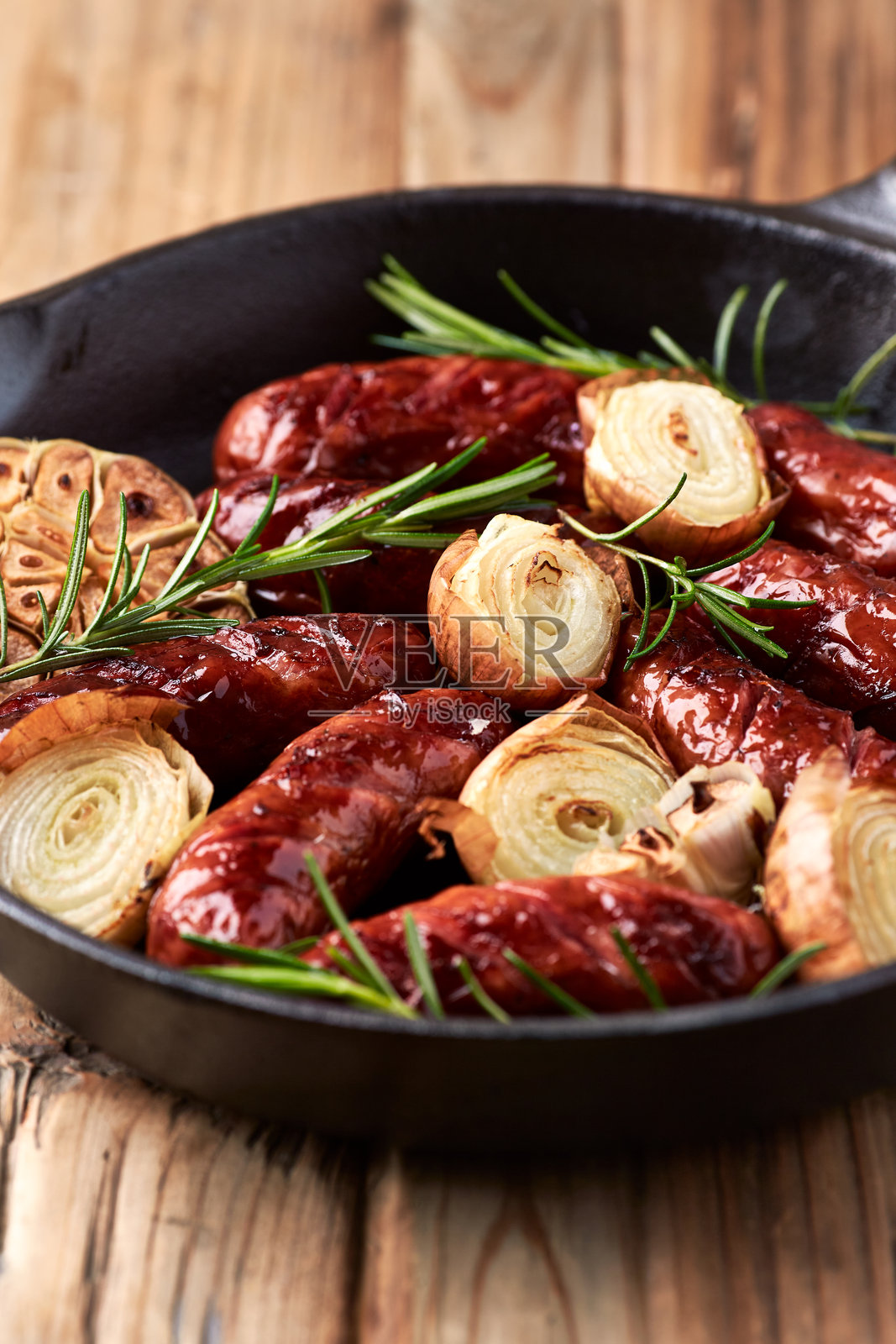 铸铁锅中煎炸香肠,配以新鲜迷迭香。特写。照片摄影图片