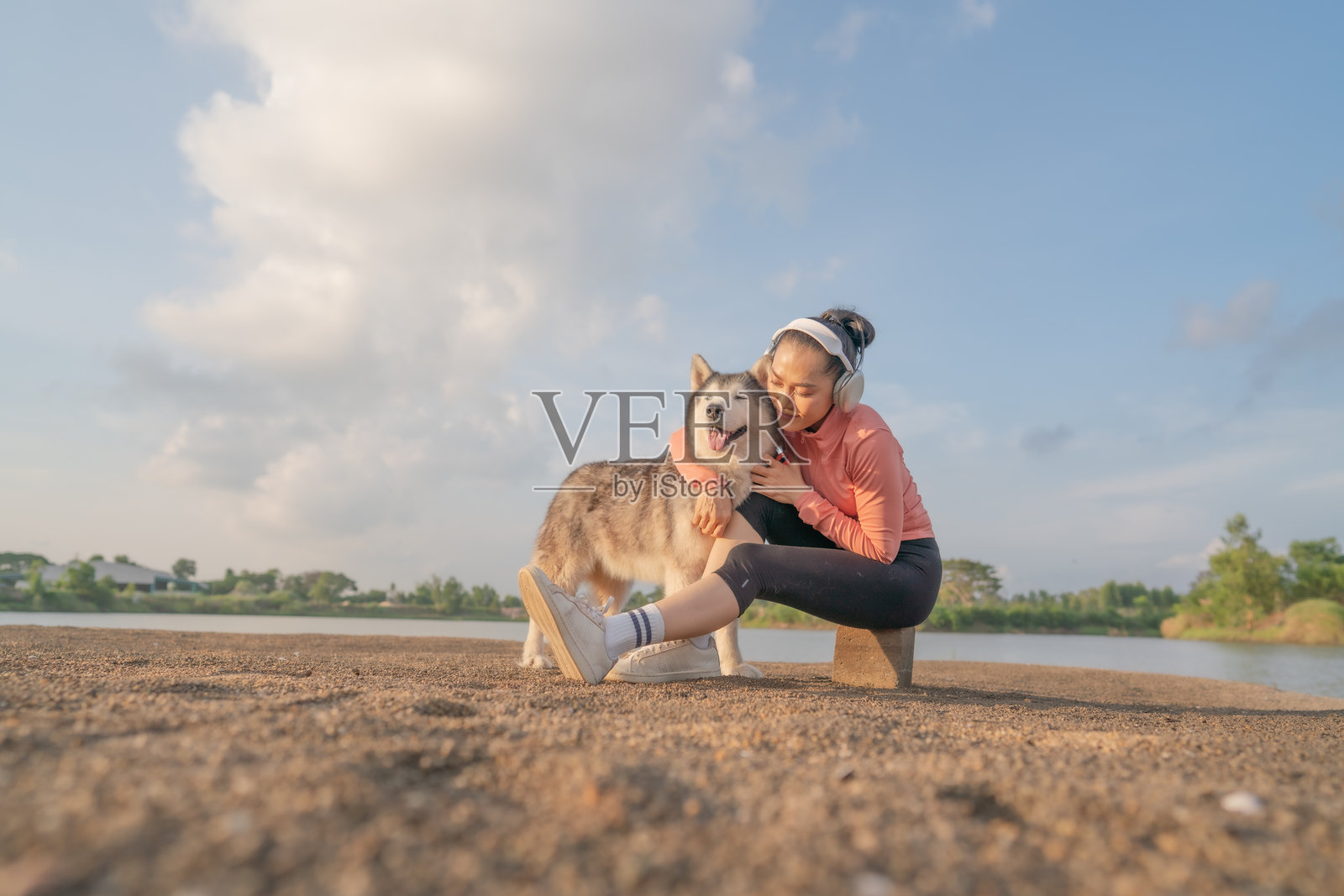 一位女性在湖边沙滩上遛狗,听着音乐,尤其是在日落时分。照片摄影图片