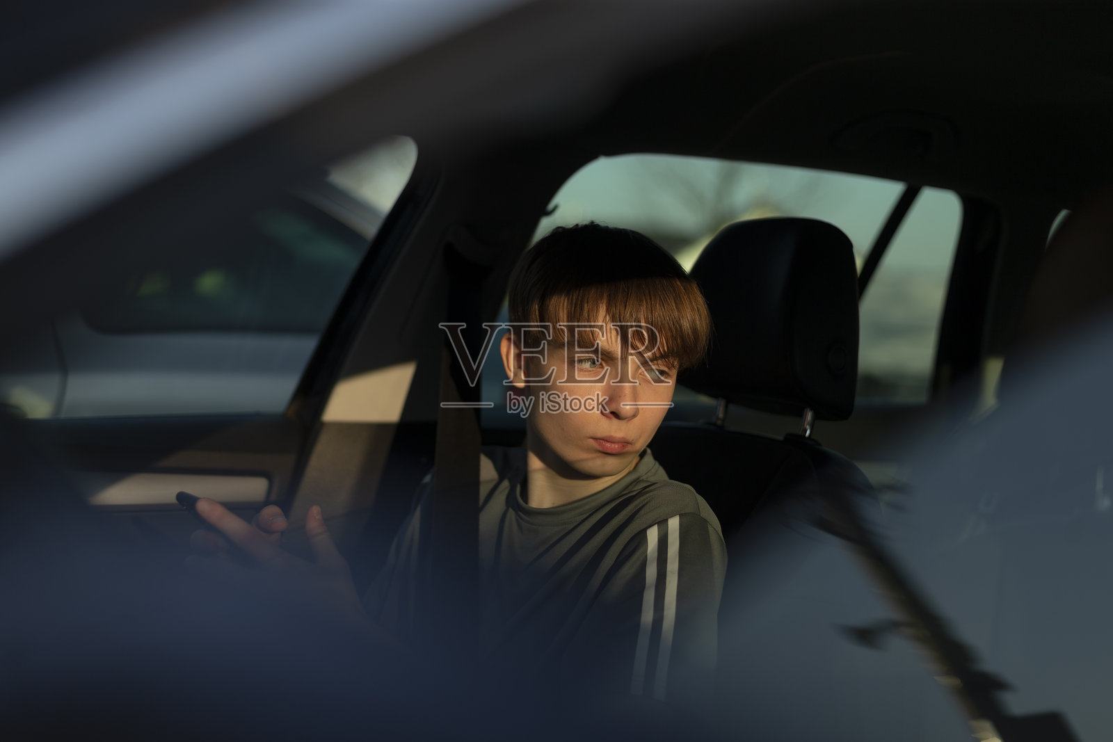 坐在车里的年轻人,背景中有倒影照片摄影图片