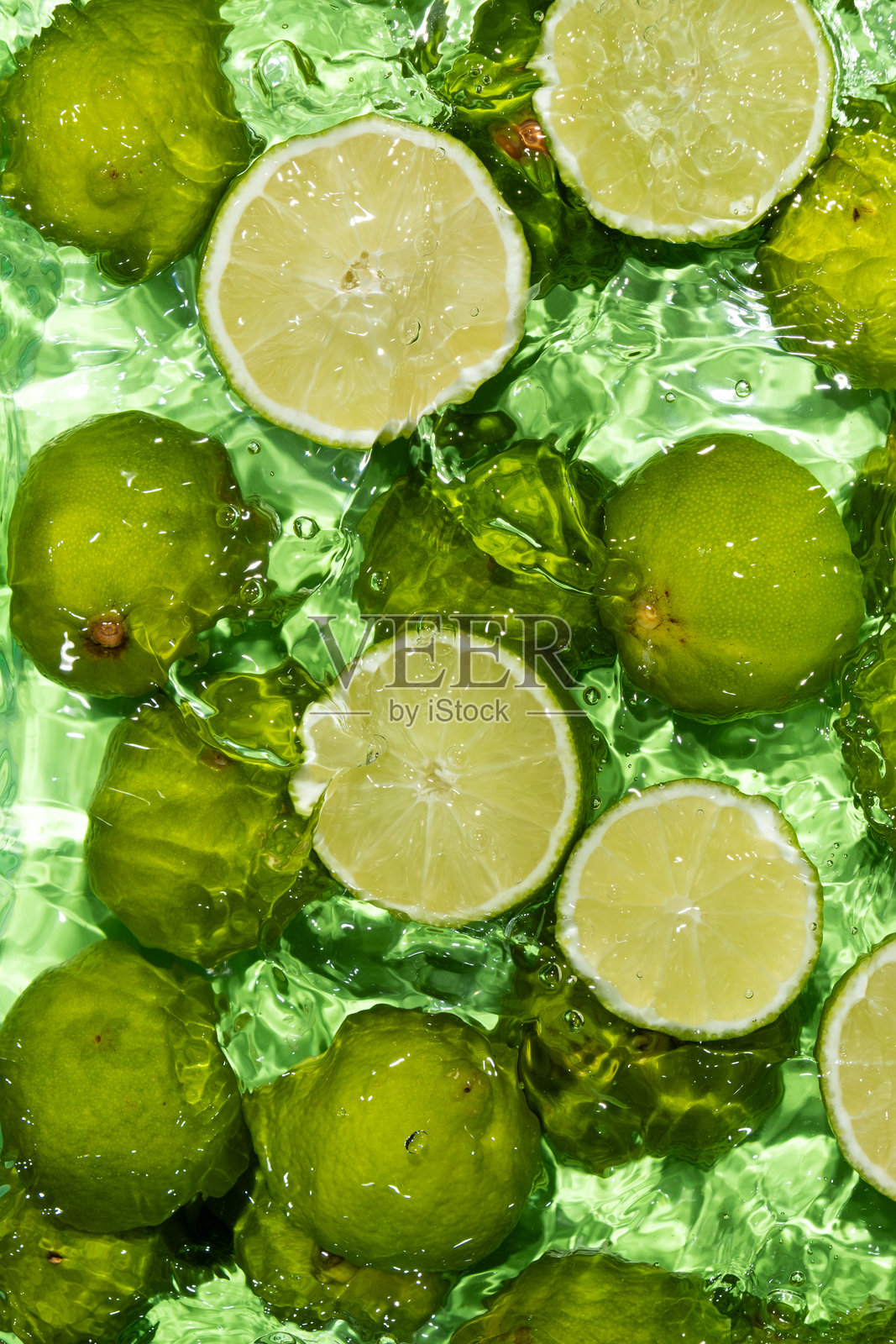 热带水果飞溅,青柠半片在水中照片摄影图片