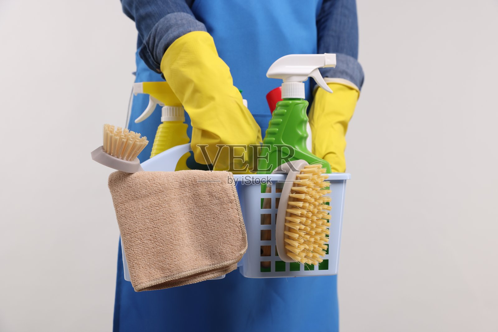手持清洁用品篮子的女性,浅色背景,特写镜头照片摄影图片