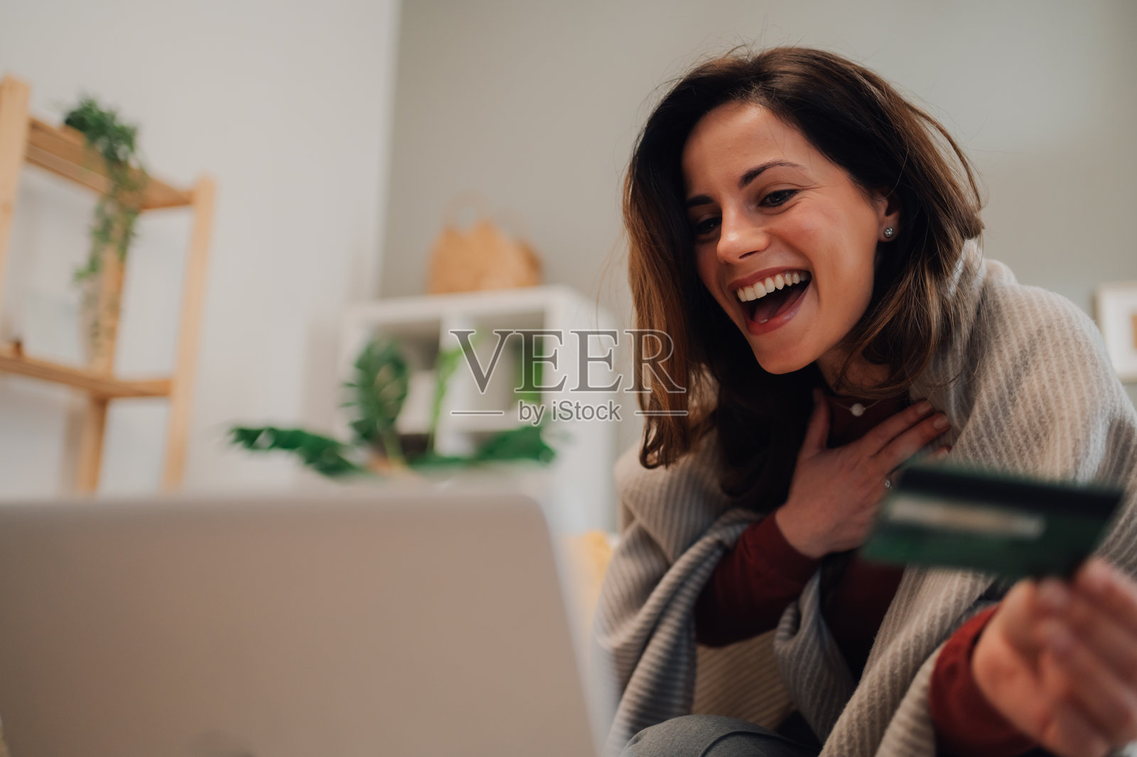 兴奋的女性在家中使用笔记本电脑和信用卡进行在线购物照片摄影图片