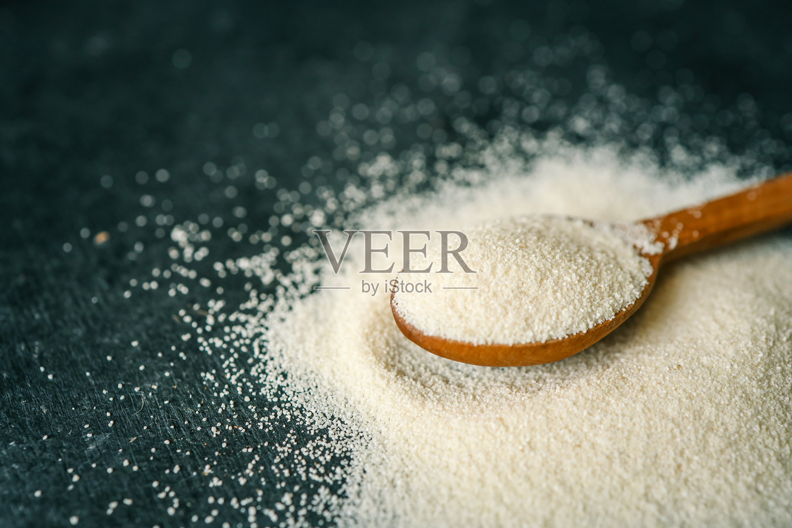 木勺中的粗麦粉特写,背景有一个碗。柔和的自然光线突显了细腻的质感和温暖的色调。照片摄影图片