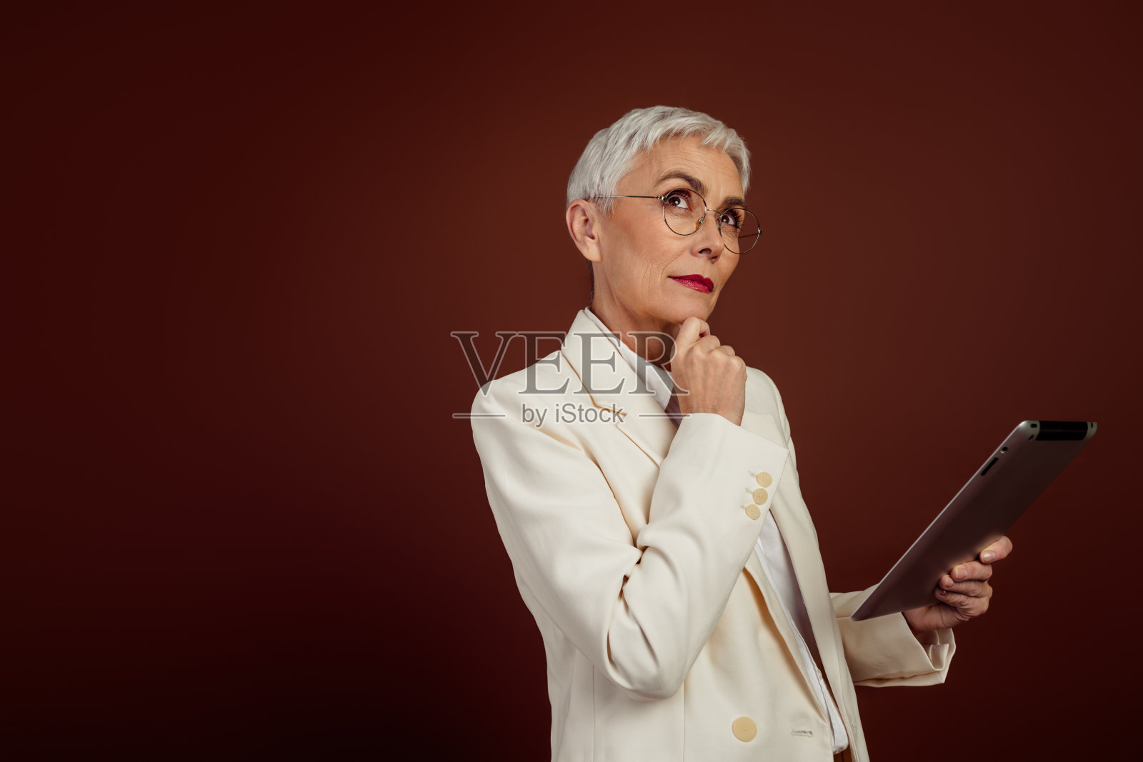 自信的成熟的女性穿着时尚的白色西装坐在椅子上,散发出优雅和专业的气质照片摄影图片