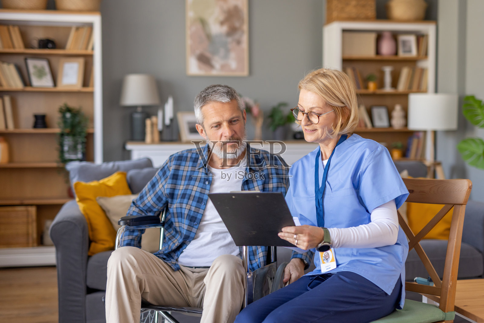 护理人员在家中与老年男性查看健康记录照片摄影图片