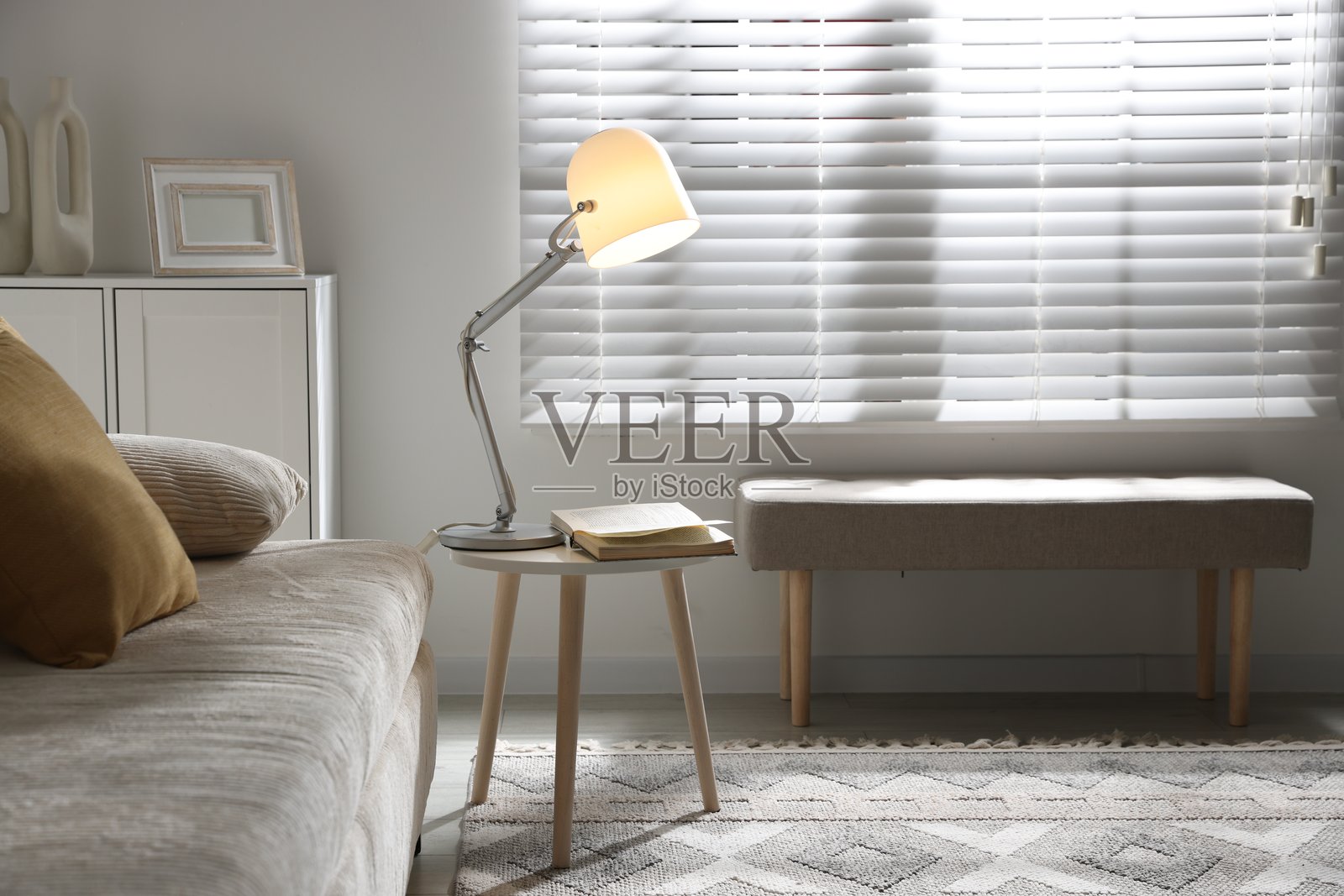 时尚的夜灯和沙发旁边的书在边桌上。室内设计照片摄影图片