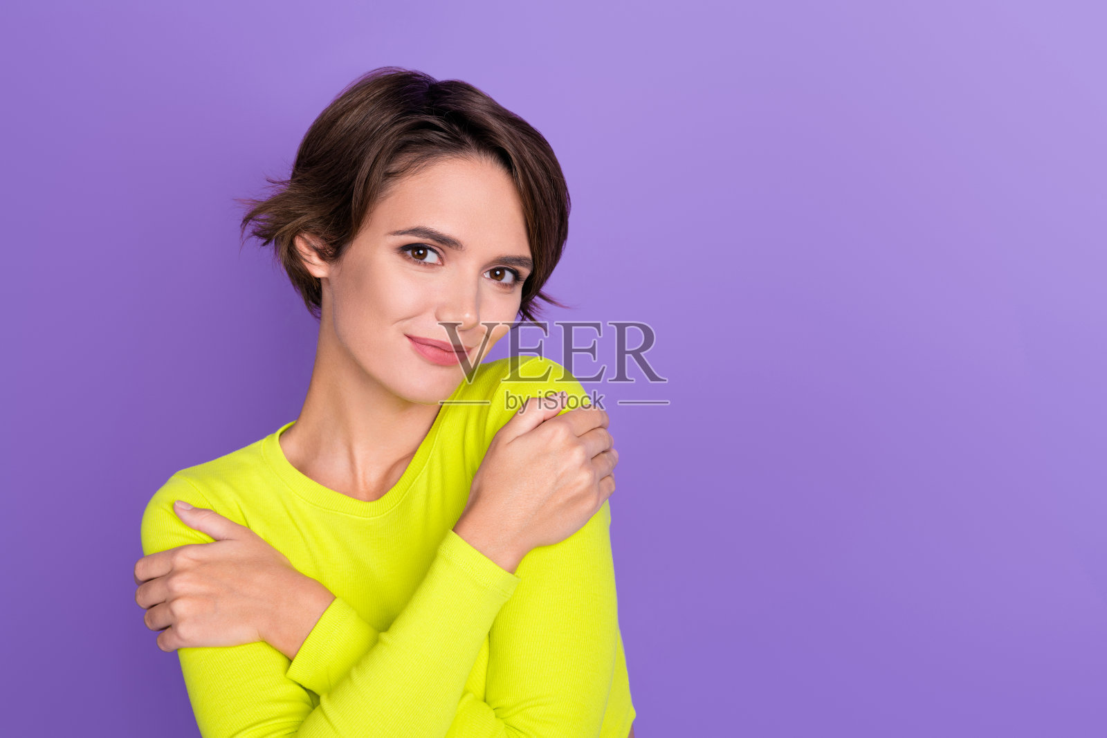 漂亮积极的女士抱着肩膀,空白的广告空间,紫色背景上独立展示照片摄影图片