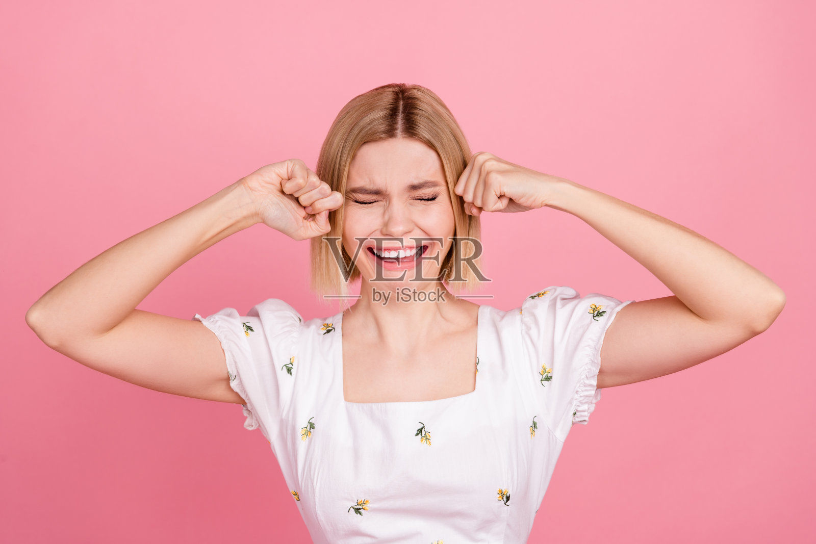 孤独女孩的肖像,皱眉流泪,穿着白色衬衫,心情不快,悲伤,失望,孤立在粉色背景上。照片摄影图片