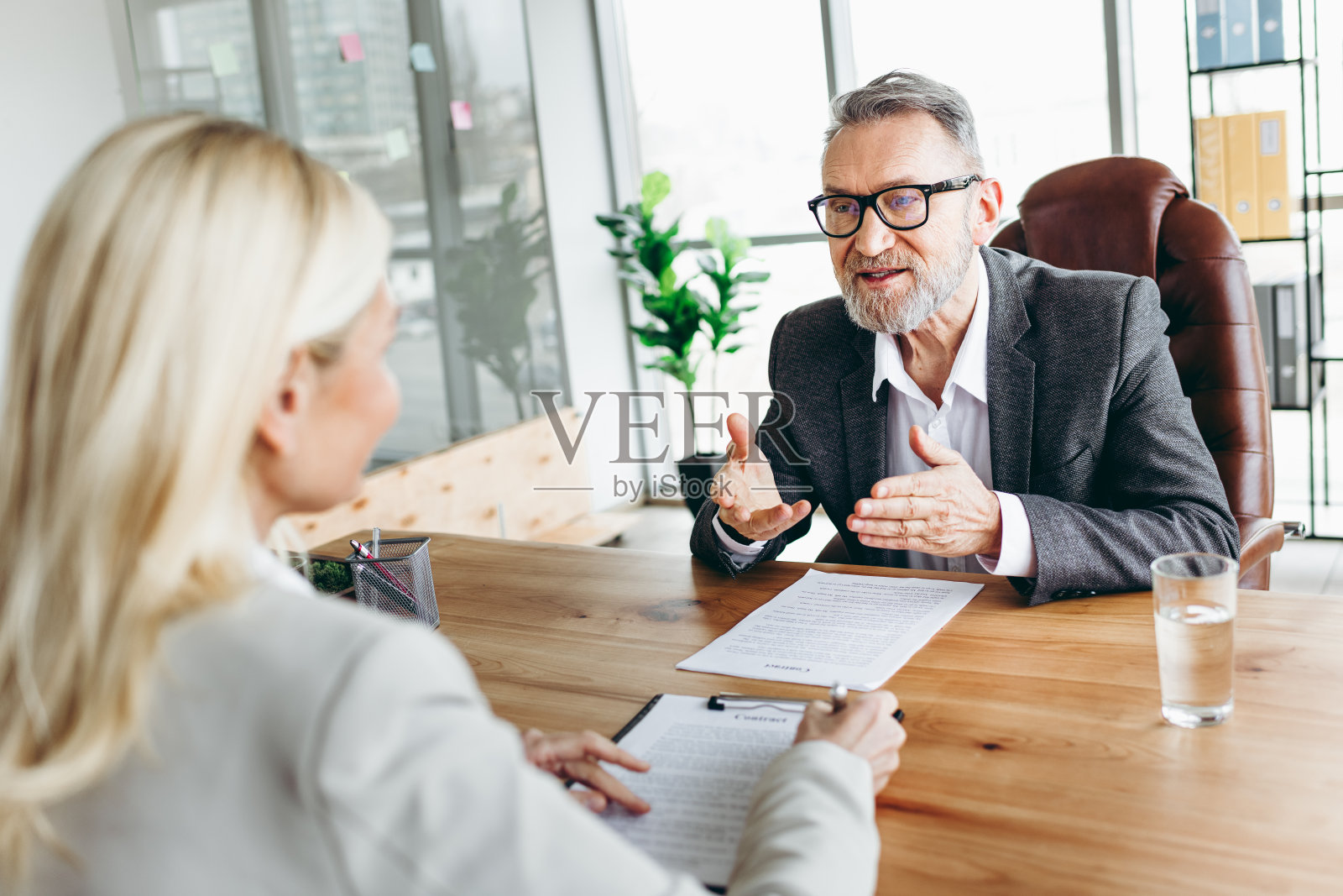 高级商务人士与女性同事在办公室环境中进行专业讨论,同时审阅文件。照片摄影图片