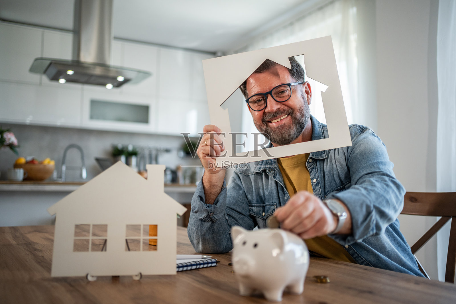 男人在储蓄罐里存钱以购买新房子照片摄影图片