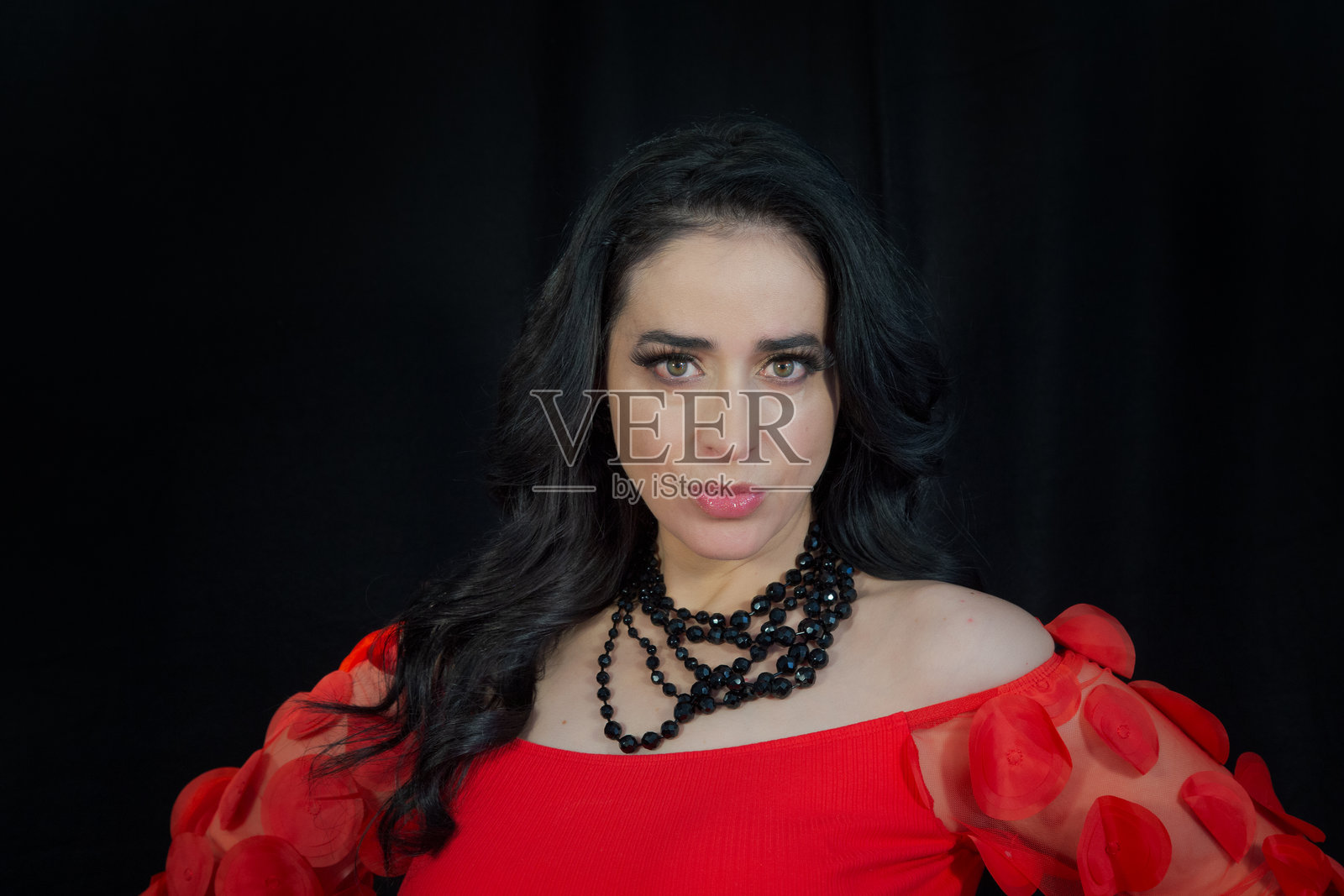 穿着红色连衣裙和黑色项链的拉丁裔墨西哥女性在摄影棚中摆姿势照片摄影图片