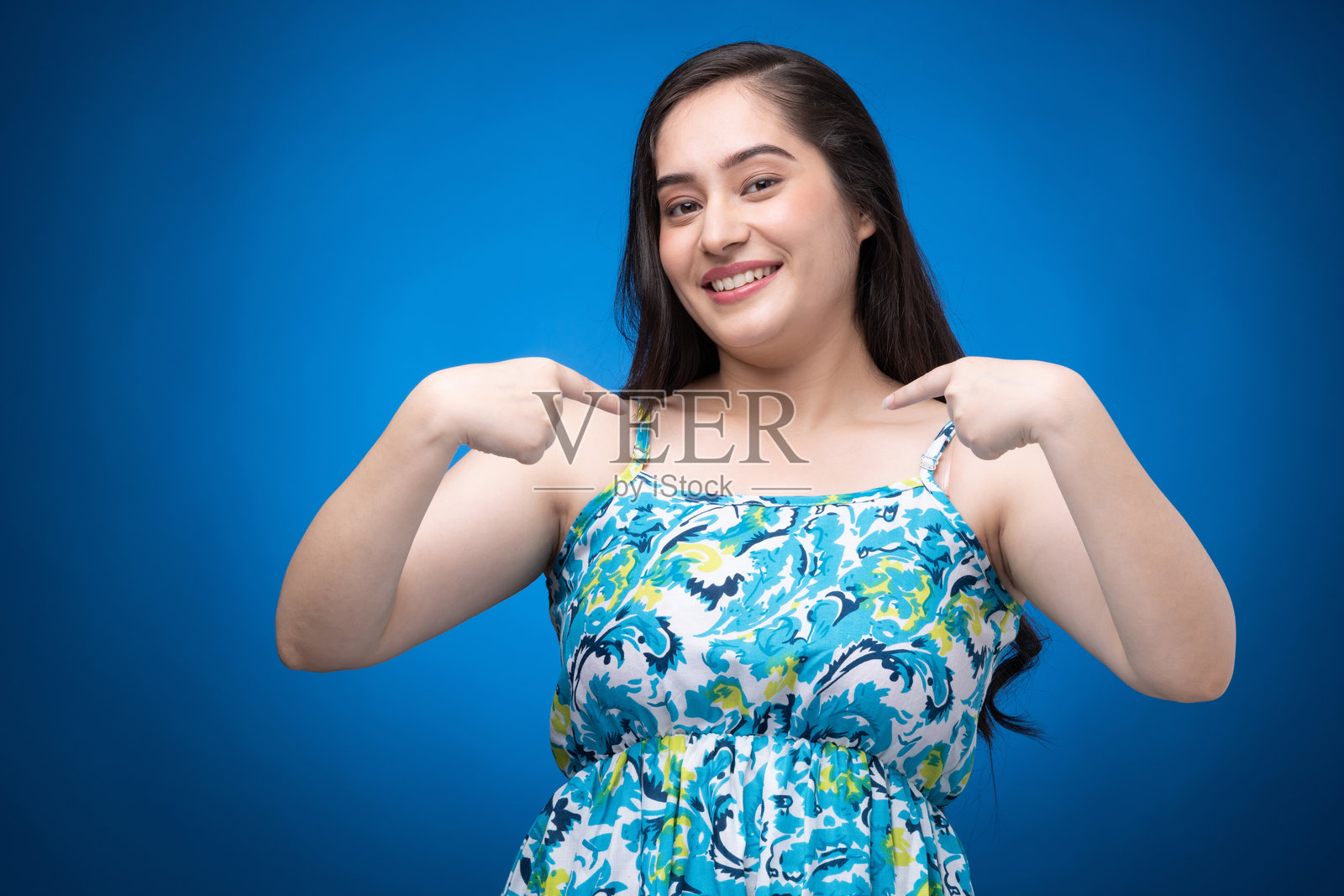 年轻女性穿着裙子的肖像,背景为蓝色照片摄影图片