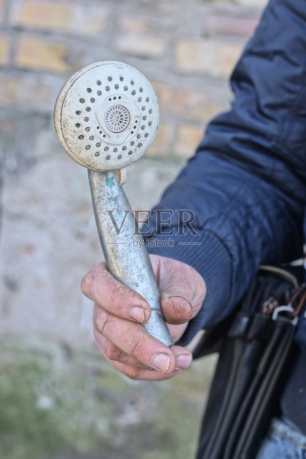 手握一个由金属和塑料制成的旧灰色淋浴头照片摄影图片