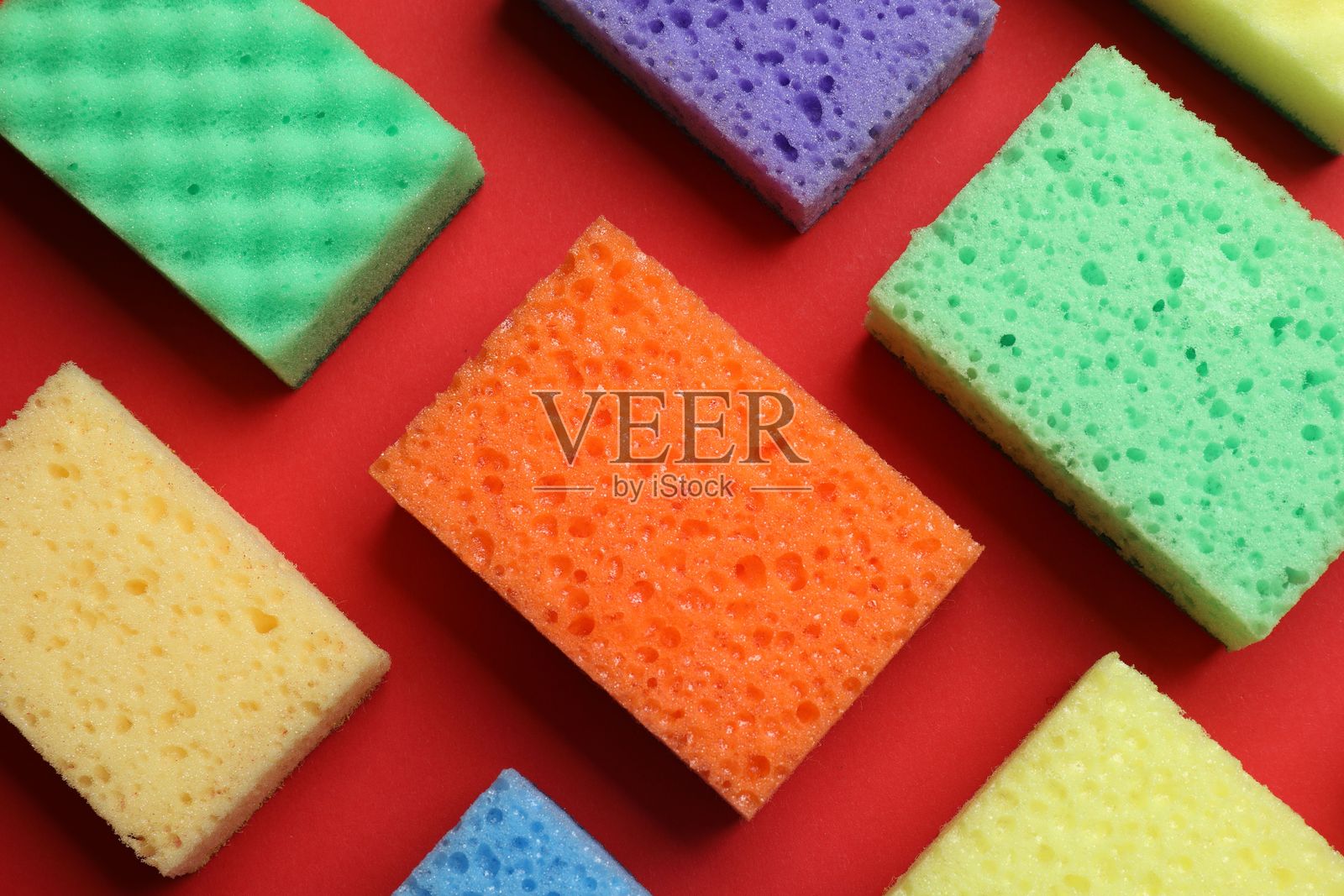 红色背景上的彩色海绵,平铺展示。清洁工具照片摄影图片