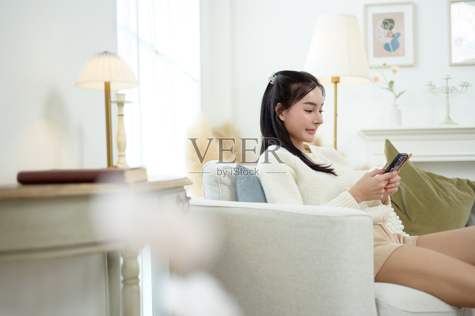 年轻的亚洲女性在家中的客厅里享受使用智能手机的时光照片摄影图片