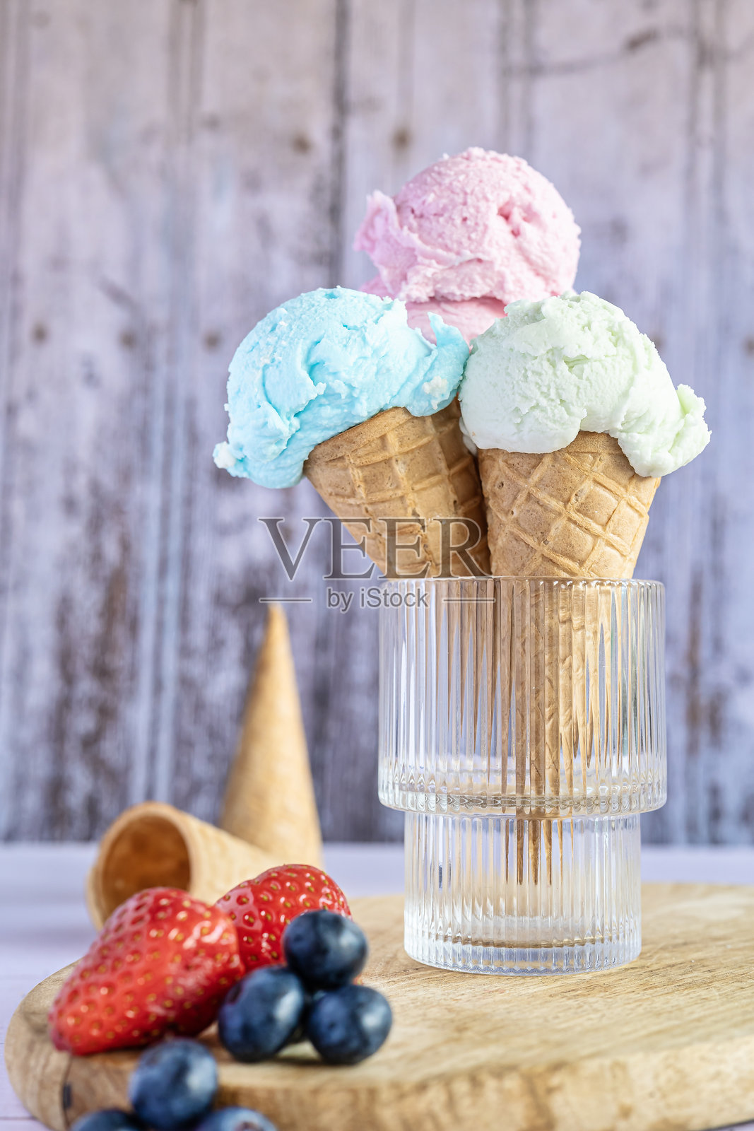 三只冰淇淋甜筒放在盛夏水果的水晶杯中照片摄影图片