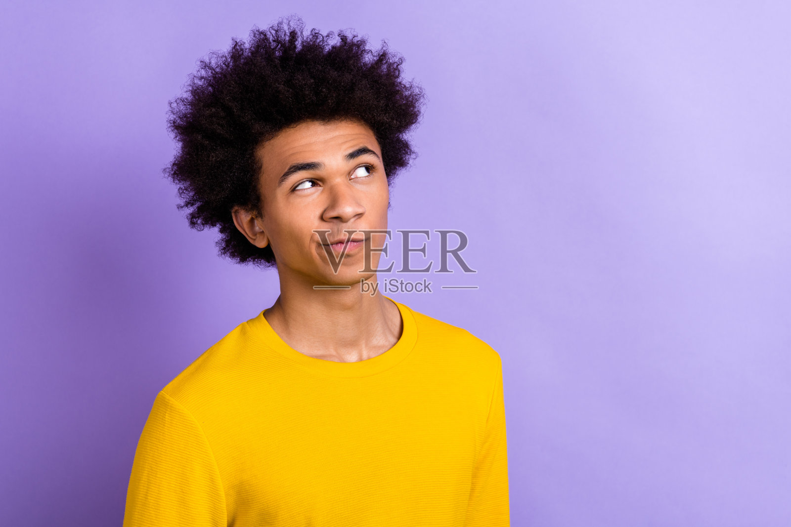 严肃深思的男士在紫色背景下独自思考,目光怀疑地注视着空旷的空间。照片摄影图片