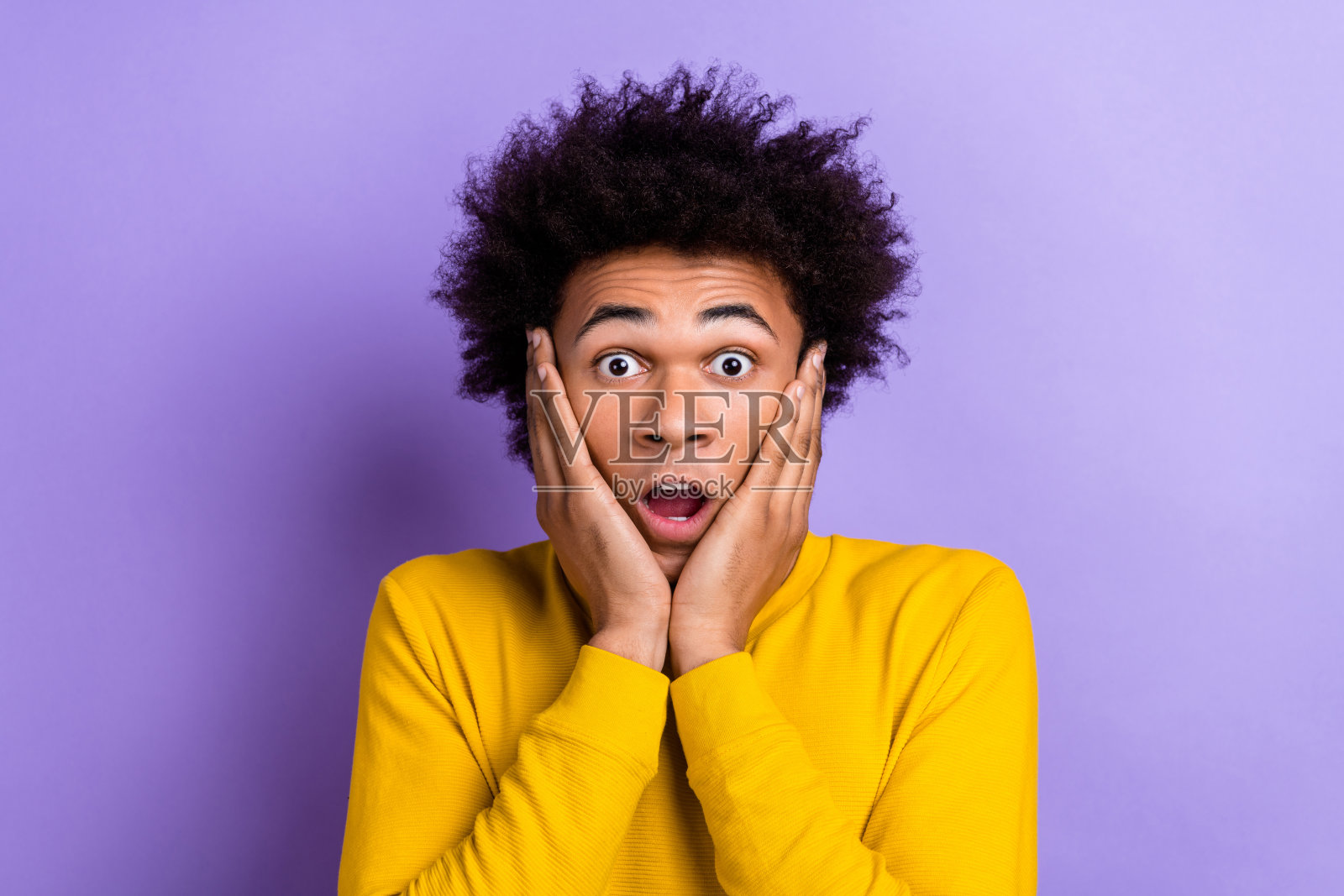 一个惊讶得说不出话的人,双手触碰着颧骨,张嘴凝视,背景为紫色。照片摄影图片